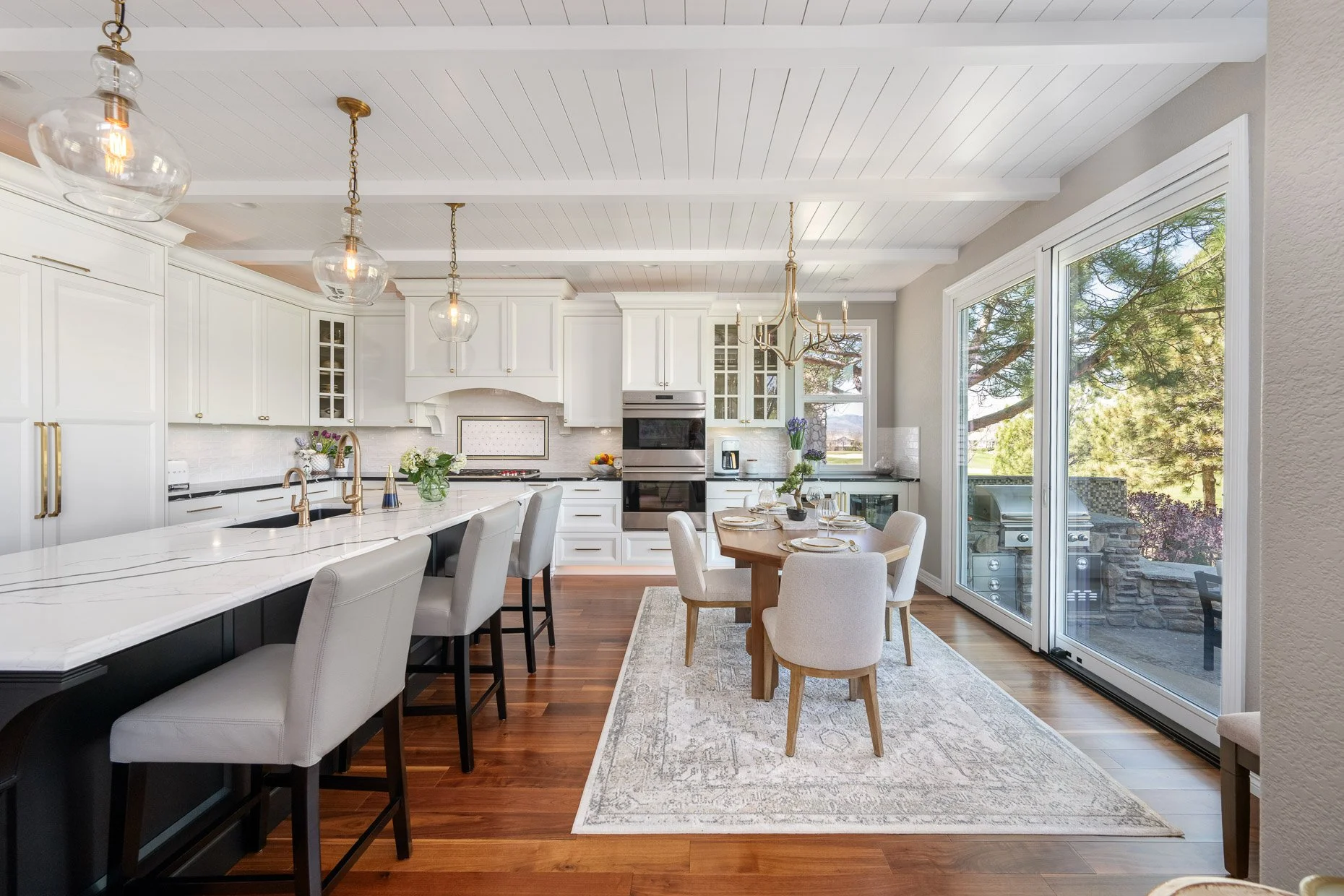 White cabinetry with black center island and marble countertop. Dine in eating area