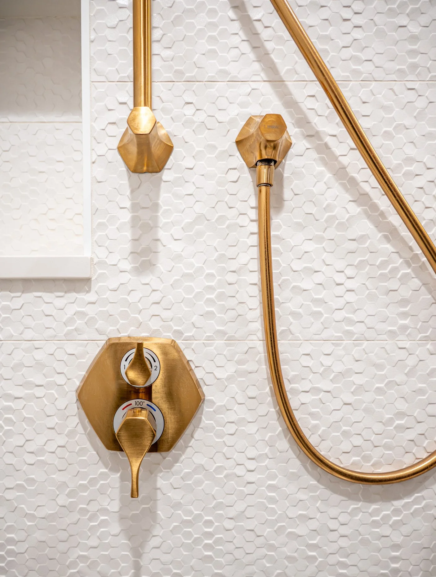 Shower detail with textured tile walls and gold fixtures