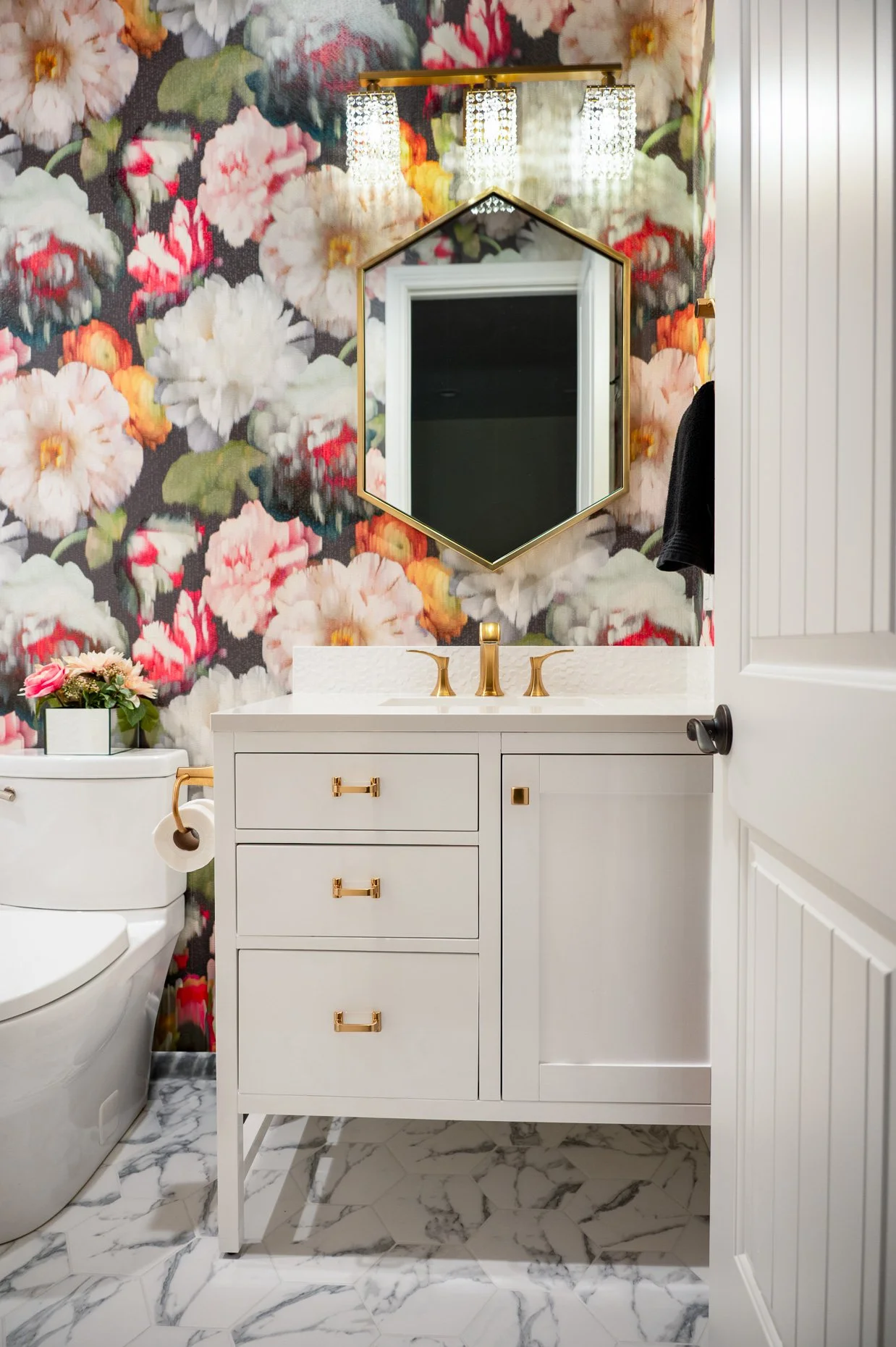 White bath cabinetry with large floral wallpaper and gold accents