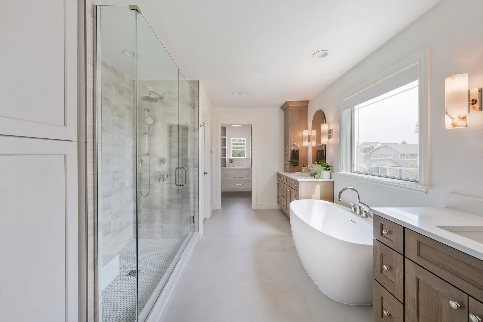 Large glass walled shower, stand alone tub, his and hers vanities