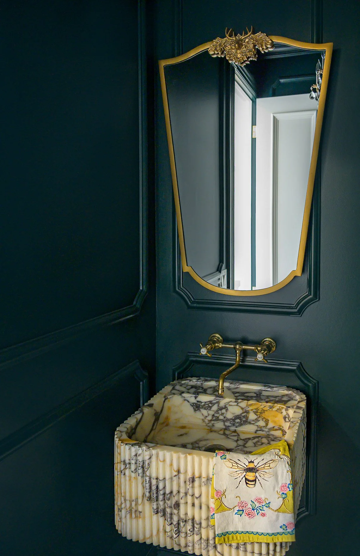 Moody, dark green powder room with gold mirror and fixtures. Exceptional stone sink for Victorian home in Denver