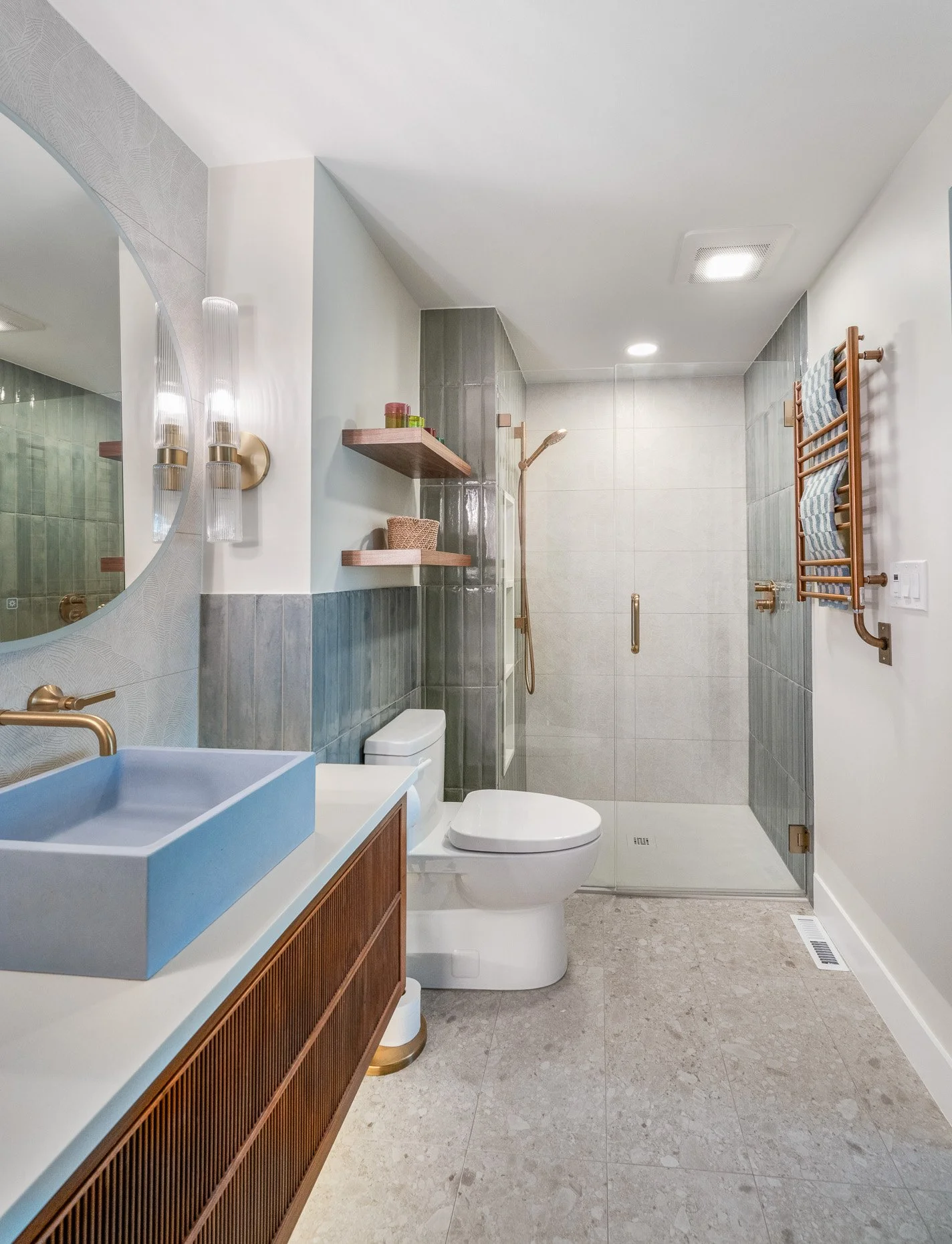Gorgeous and colorful bath with powder blue stone sink, walnut cabinetry, blue and green tile