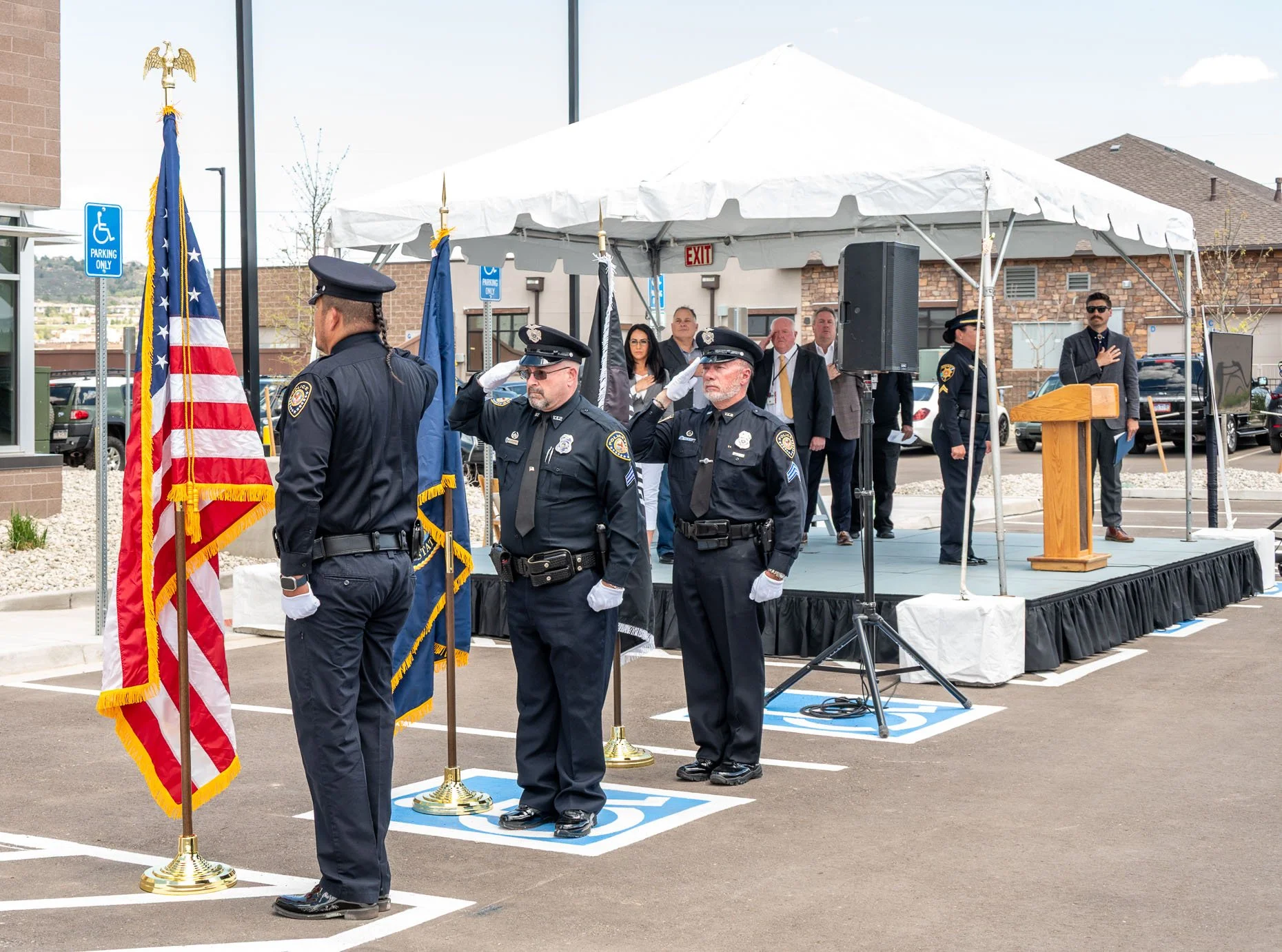 Ribbon cutting ceremony with police saluting the flag