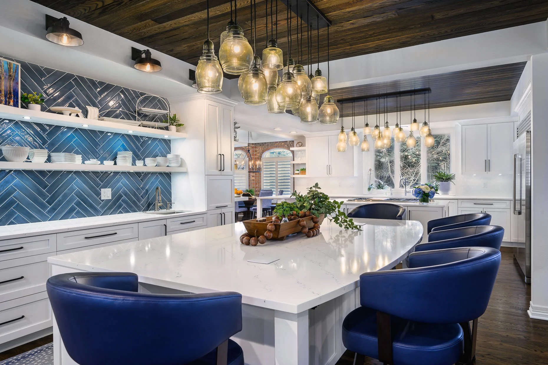 White and blue kitchen with white center island, custom blue tile, blue chairs and designer lighting