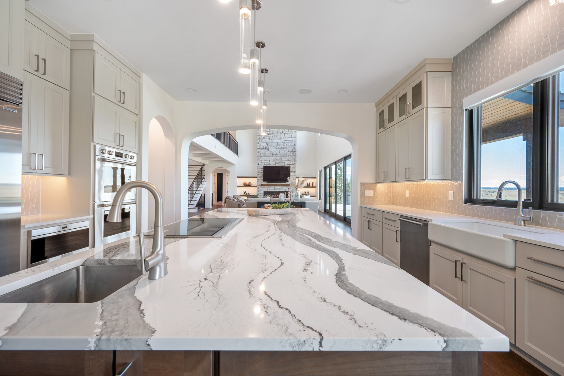 White kitchen island with gray veins running through and view of family room