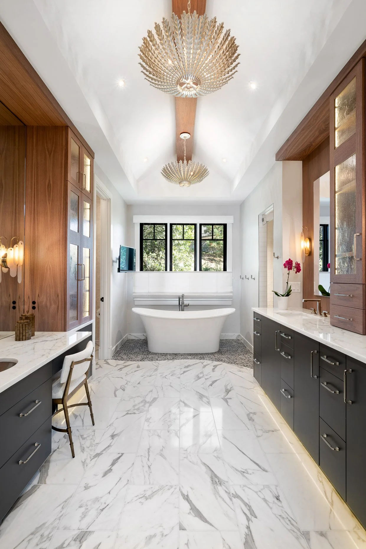 Primary bath with stand alone tub, lighted cabinetry, designer lighting and marble floors