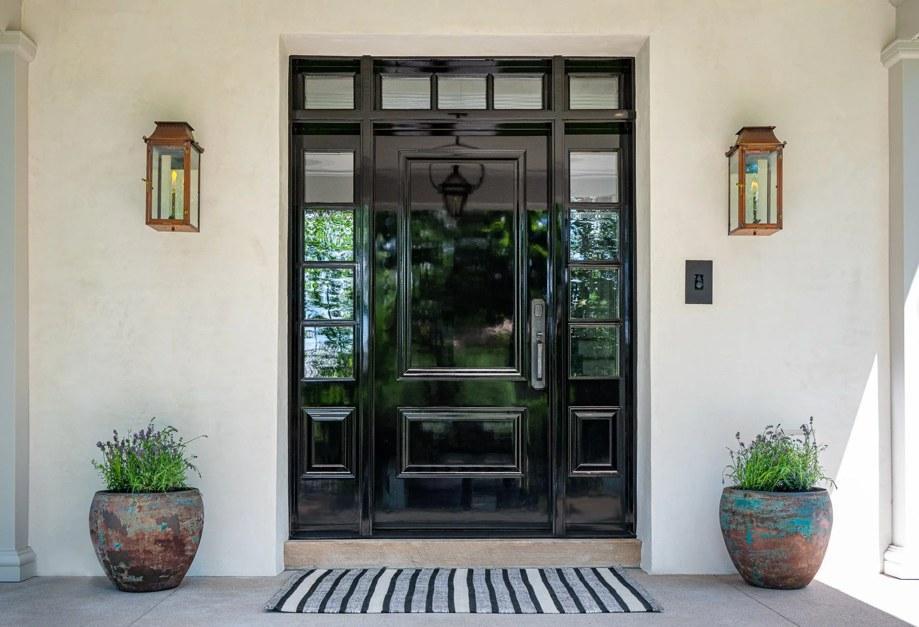 Lacquered black front door with gas lighting
