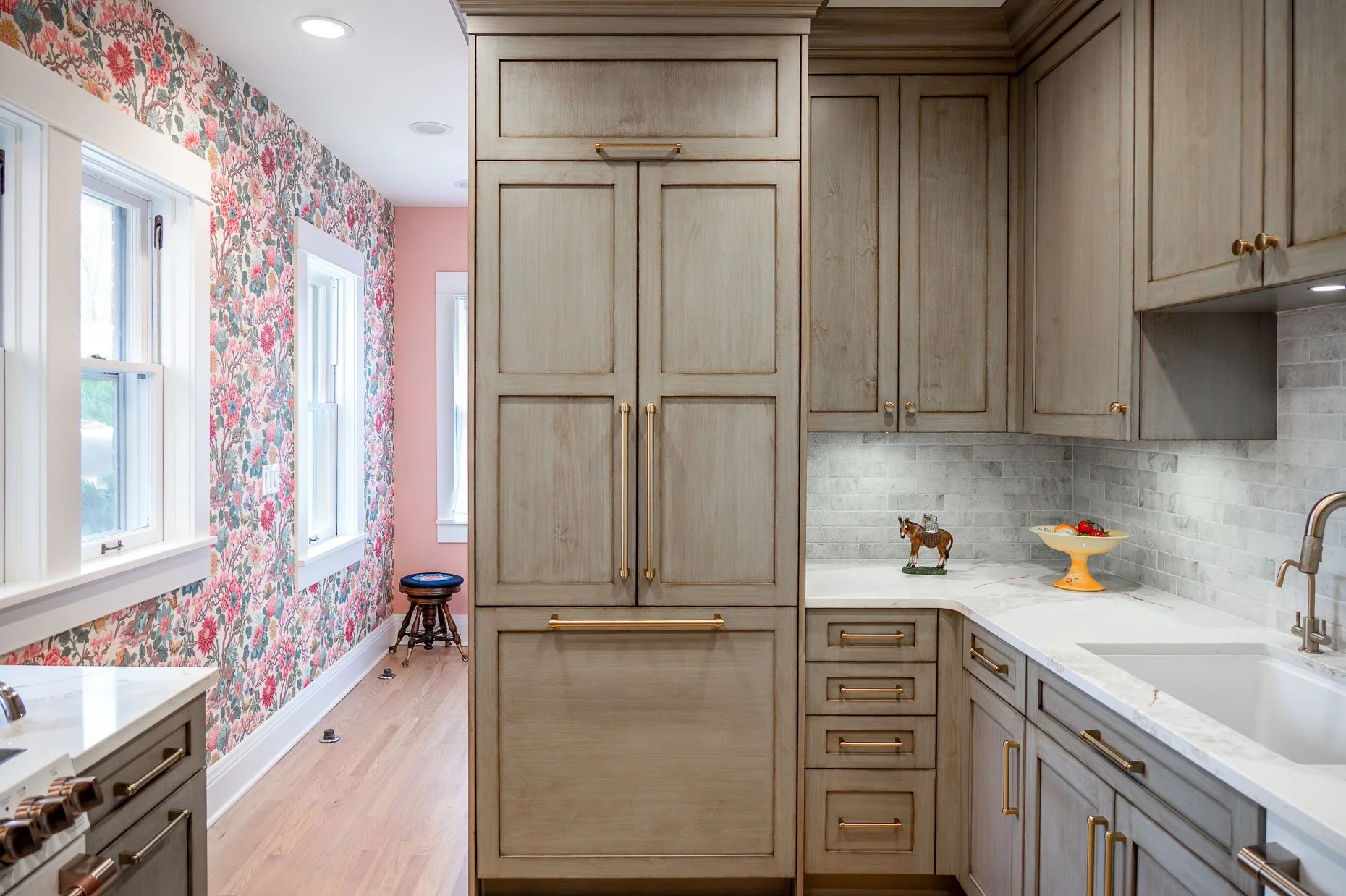 Amazing kitchen design with gold accents, long wall with flower wallpaper, and designer appliances