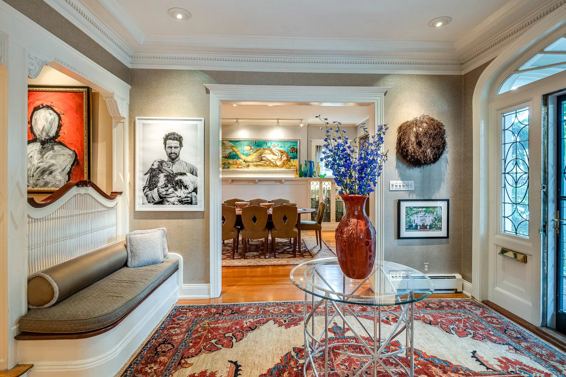 Beautiful foyer with wonderful art, center table, bench and leaded glass windows