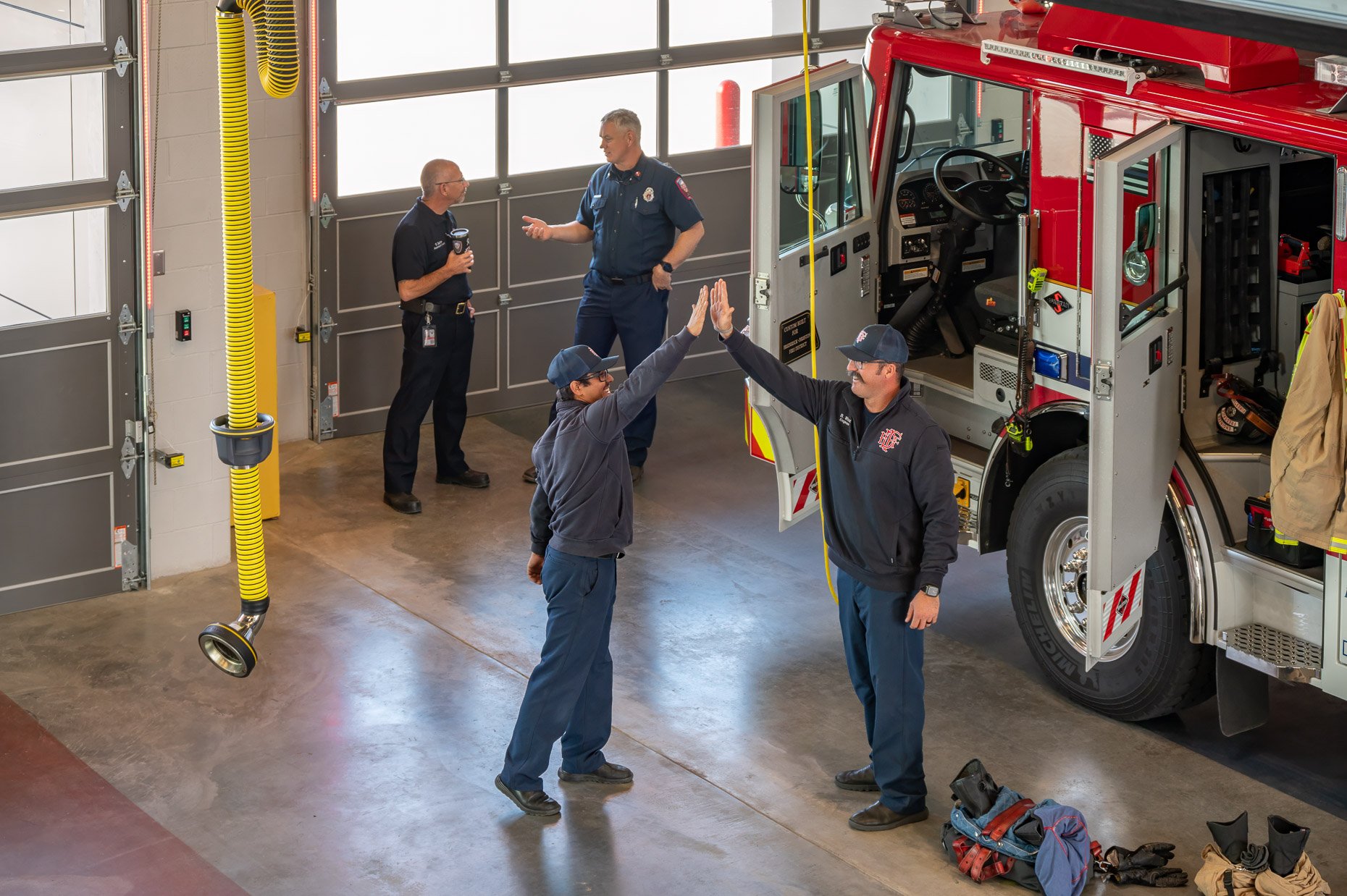 Lifestyle Photography inside fire station bay with firemen hi-fiving