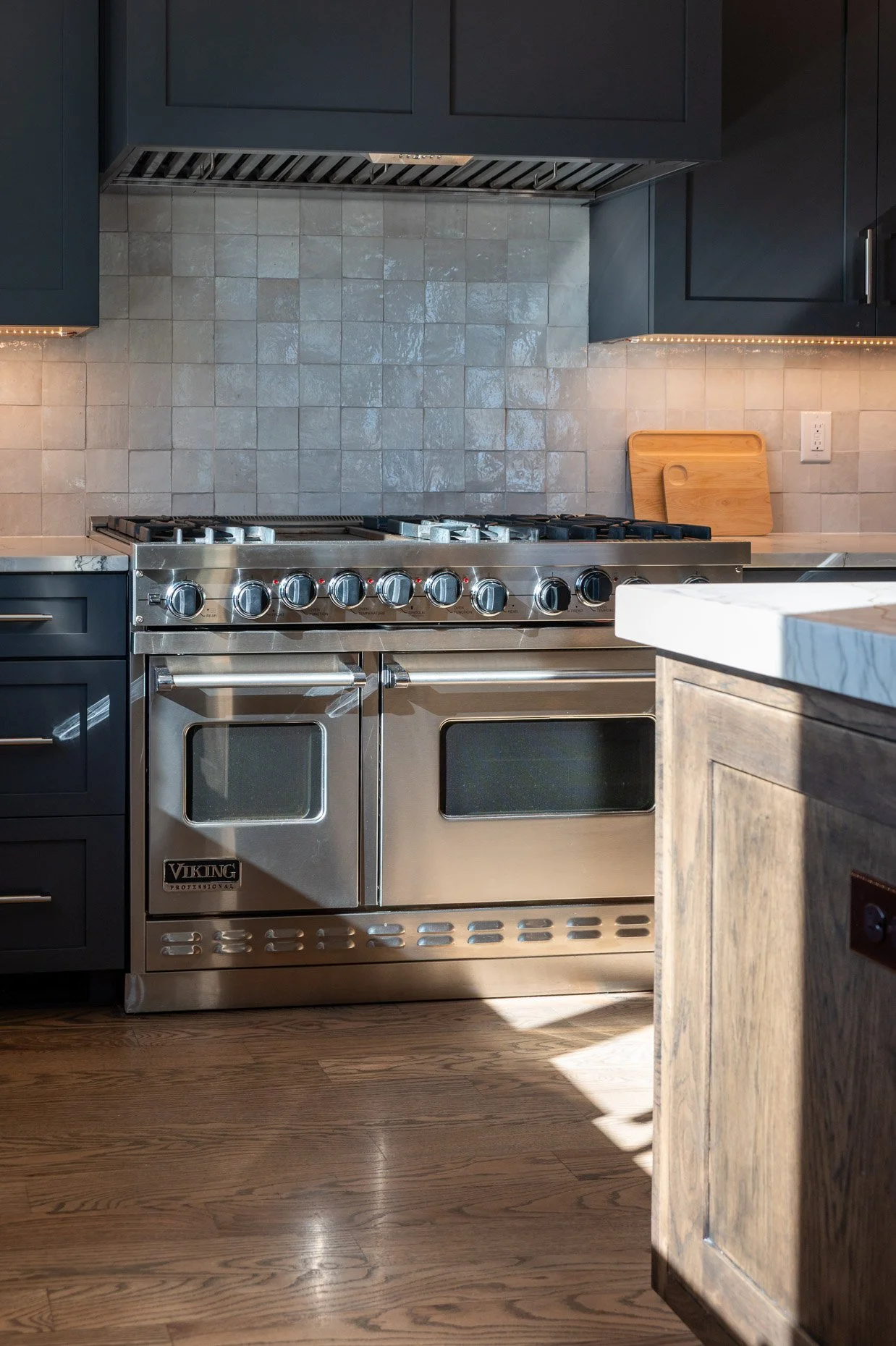 Viking stove in newly renovated home with shining backsplash and deep turquoise cabnetry