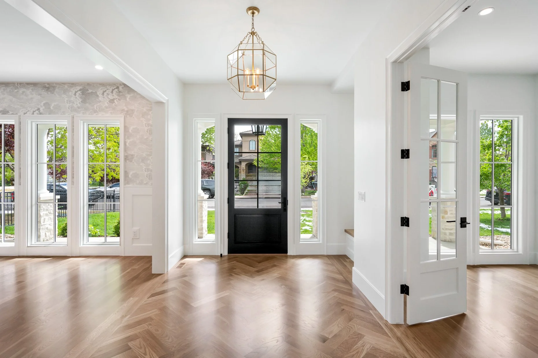 Spectacular foyer with deep, dark blue entry door and wall of windows, designer wood flooring