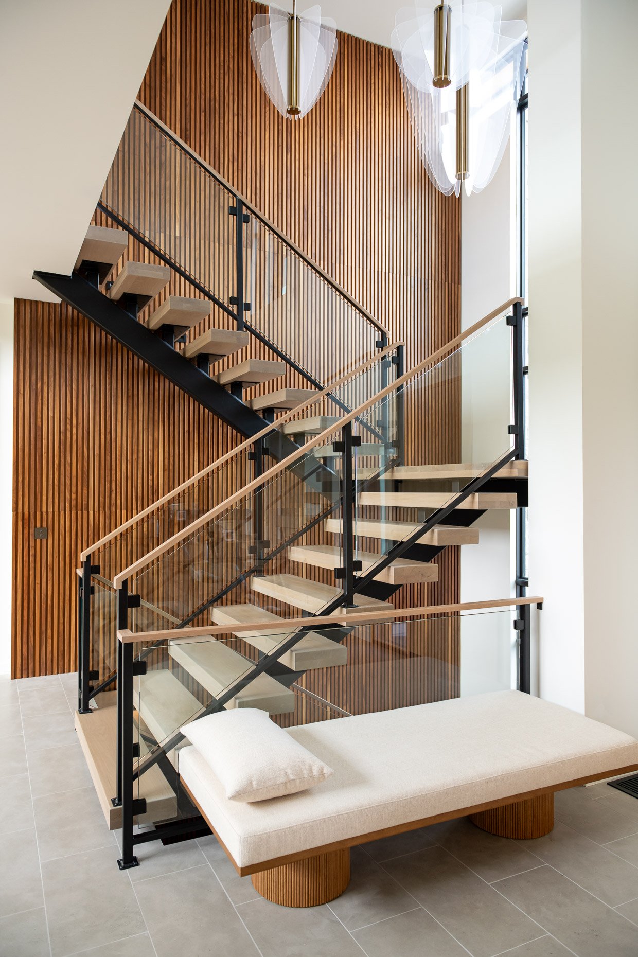 Exquisite entry with wood line open staircase, lovely lighting and chaise lounge