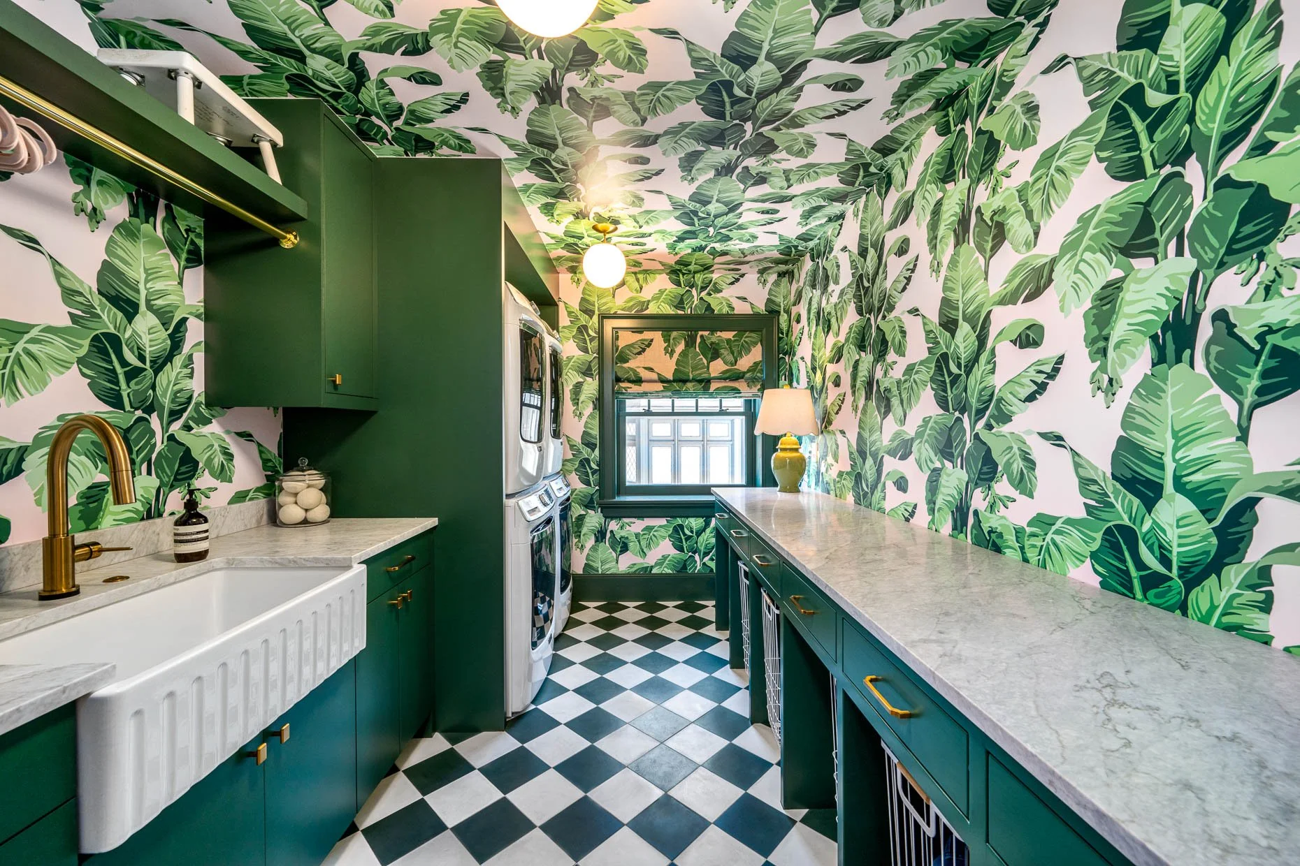 Whimsical laundry room with palm wallpaper, turquois cabinetry, farmer's sink and diamond tile flooring