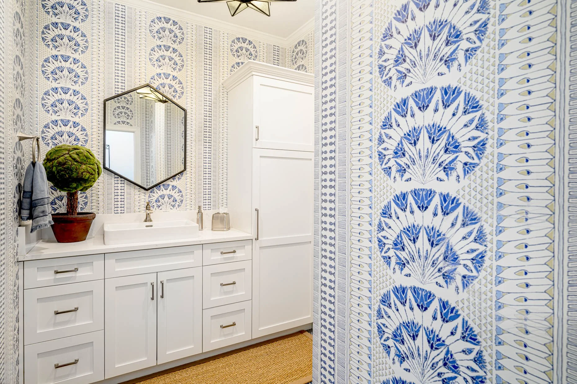 Clean and beautiful guest bath with exceptional wallpaper and white cabinetry