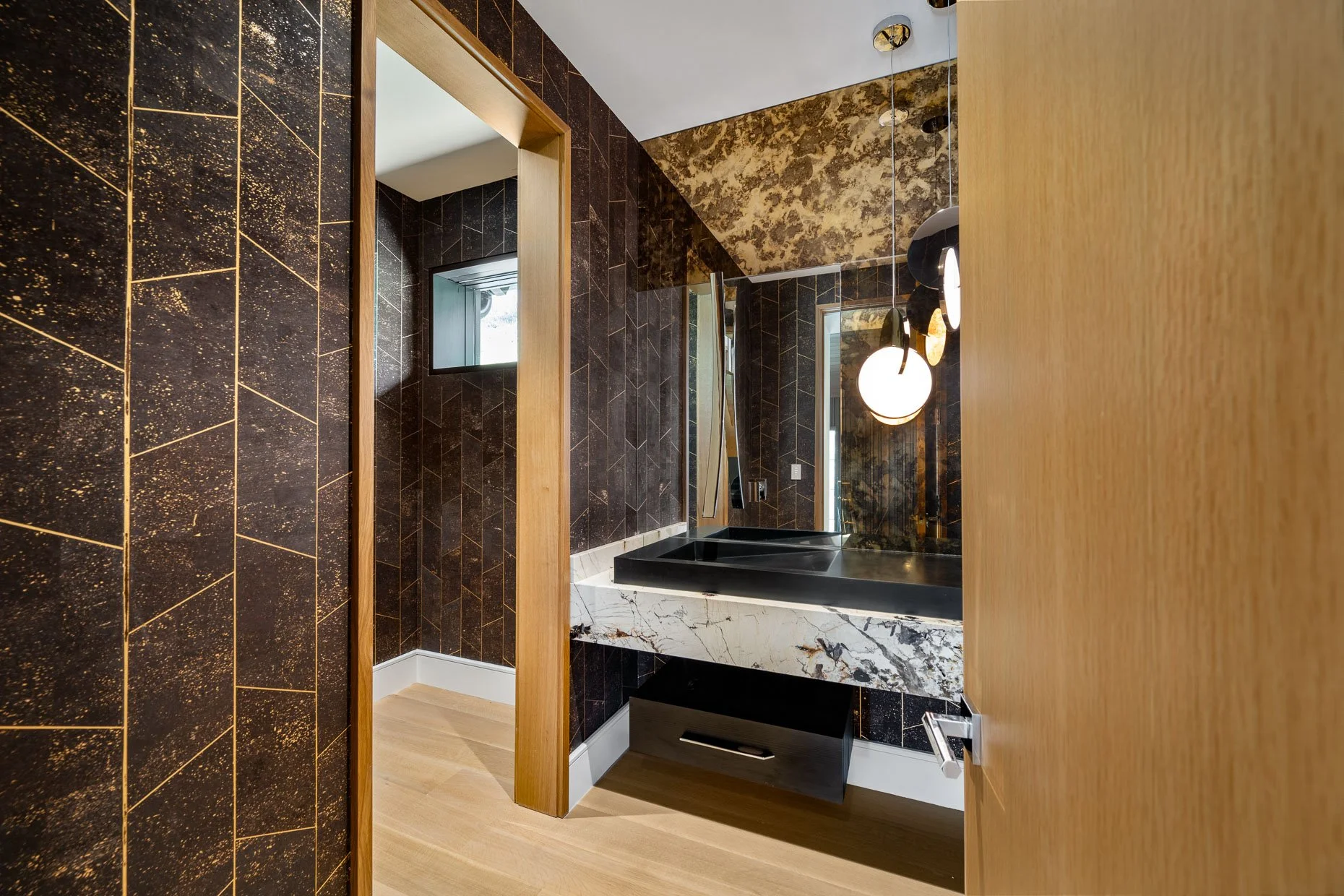 Guest powder room with gold and brown accents, white marble vanity and black sink