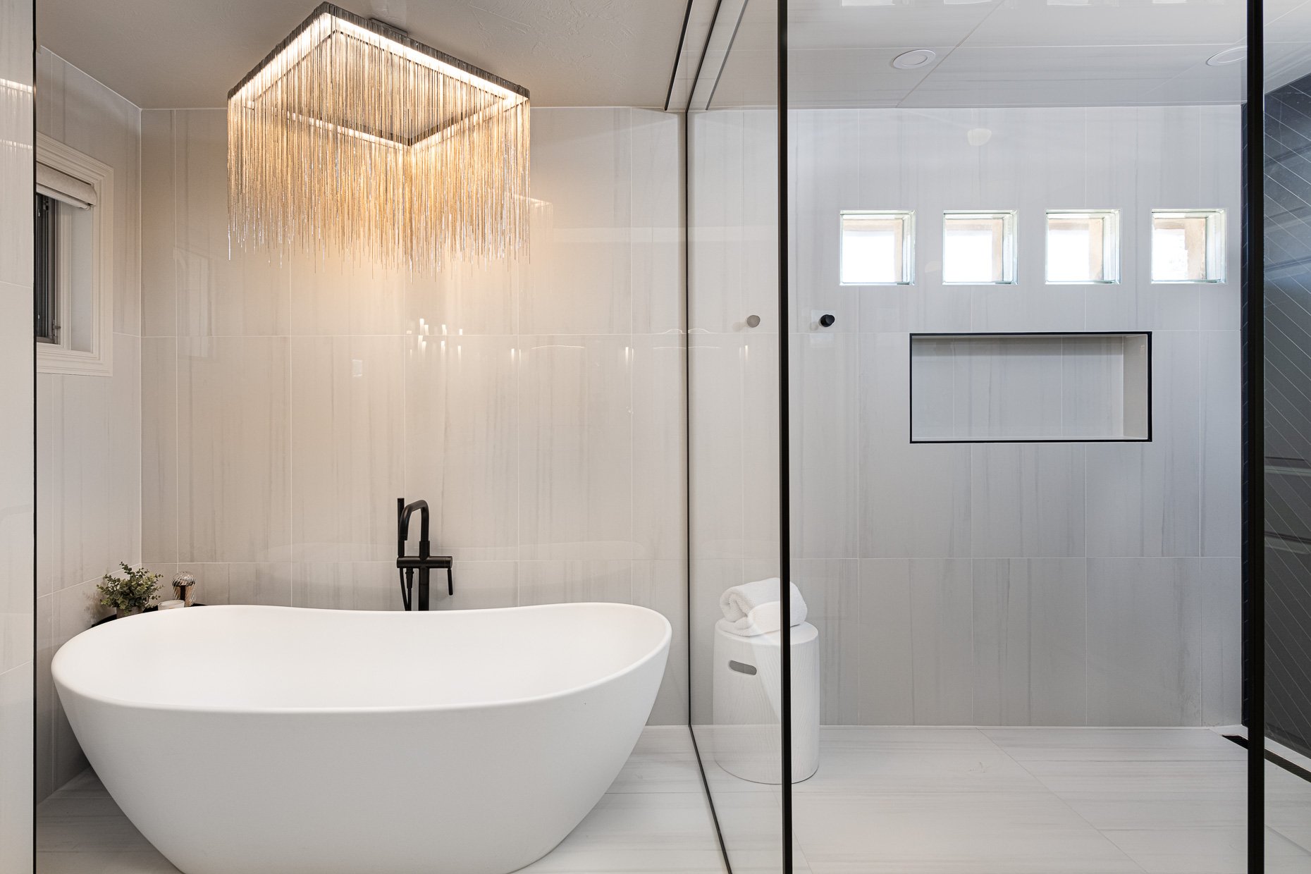 Incredible primary bath with stand alone tub, rain drop chandelier and glass walled shower