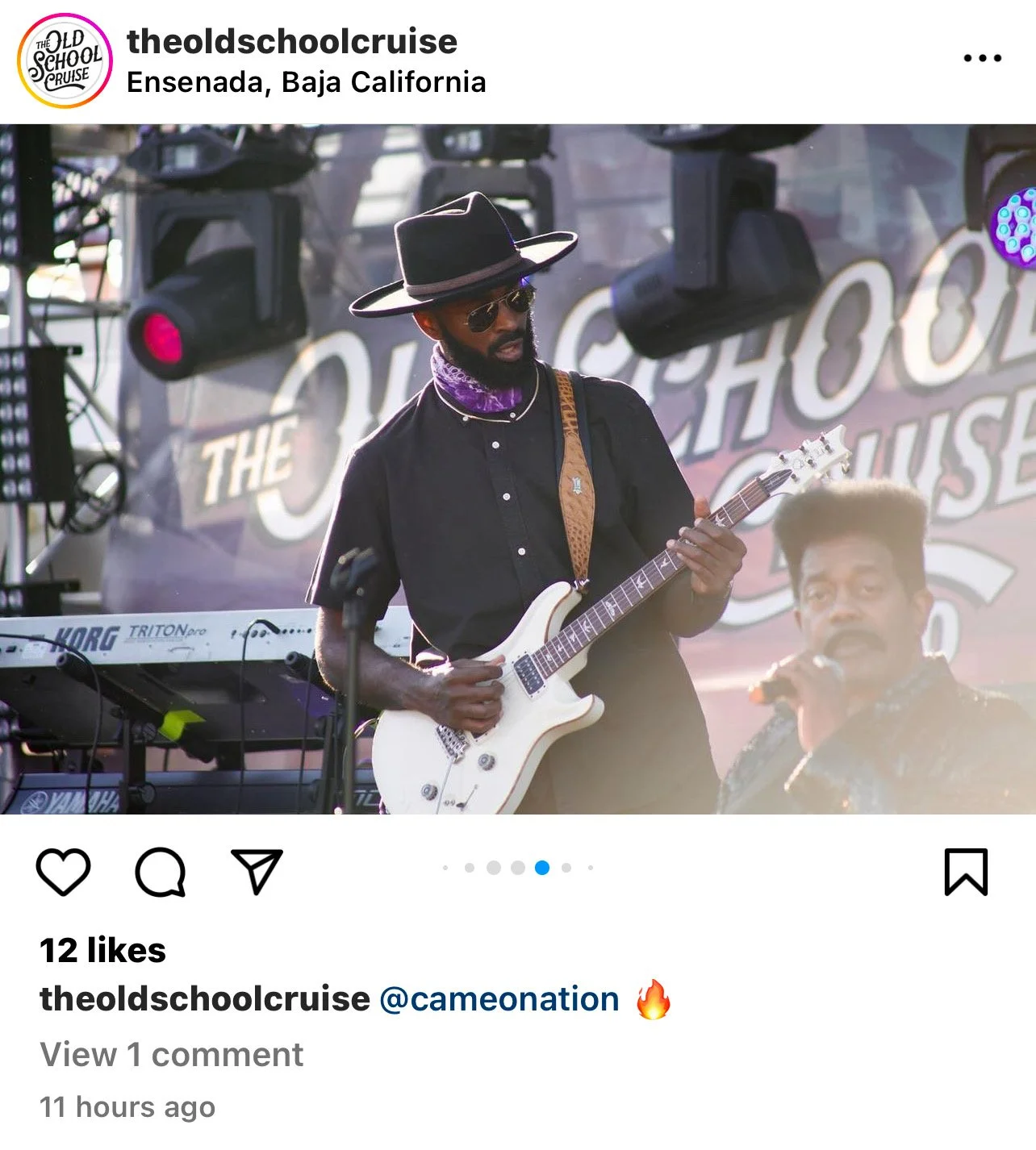 Musician wearing sunglasses, a wide-brimmed hat, and a purple bandana, playing an electric guitar on stage at an outdoor event in Ensenada, Baja California with a Sony keyboard in the background.