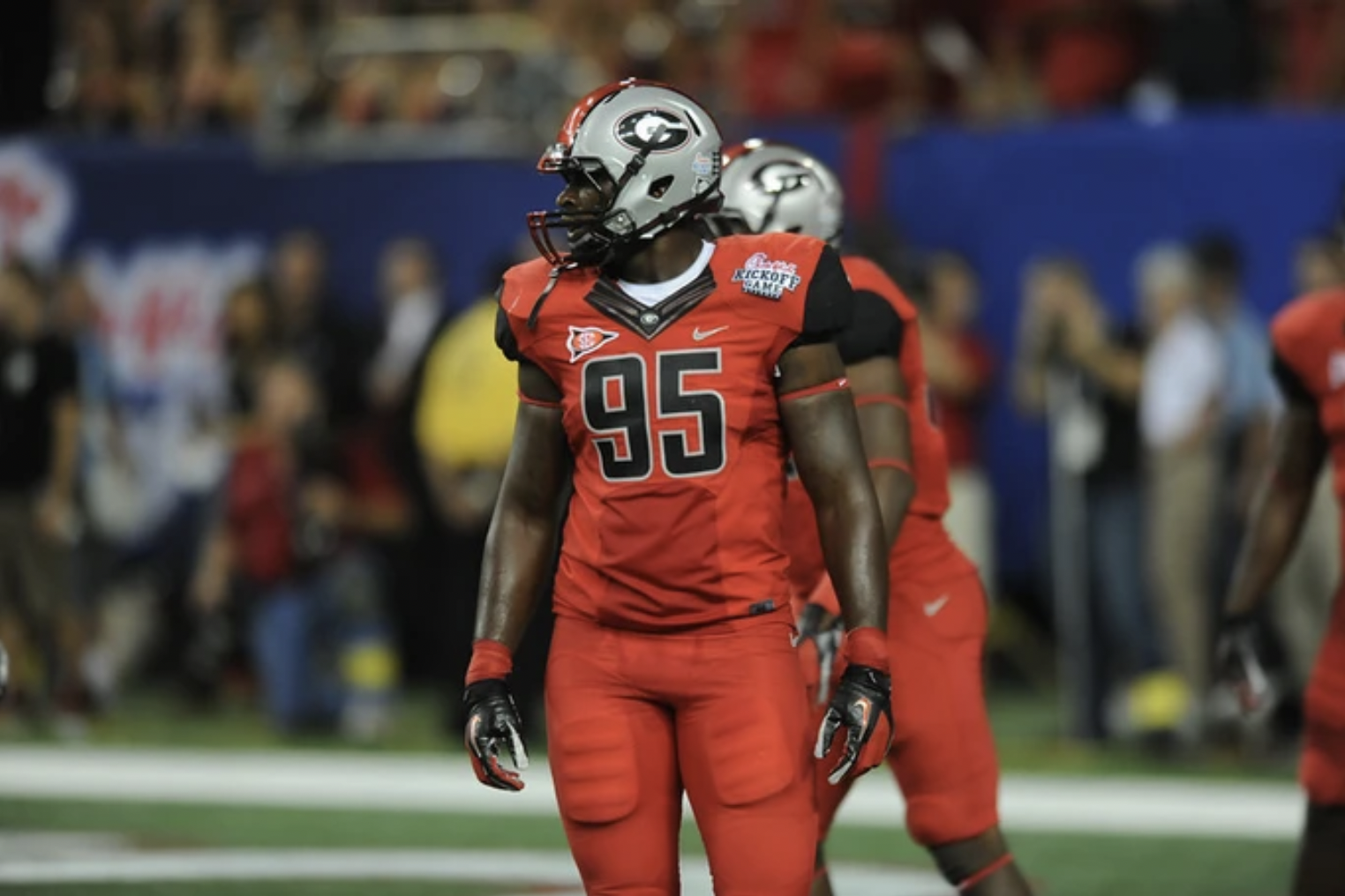 An American football player in red and black uniform with the number 95 on it, standing on the field during a game.