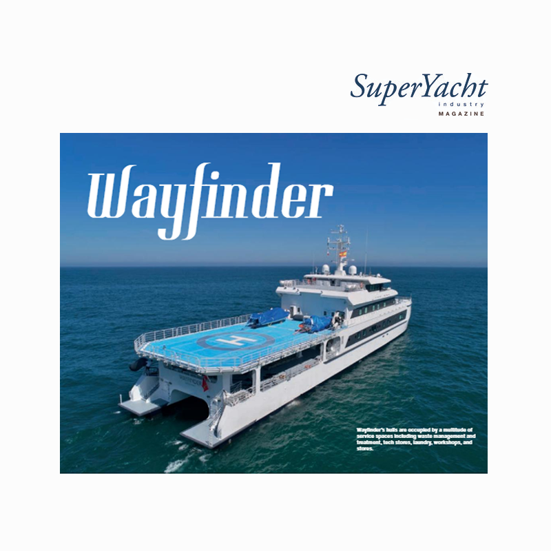 Cover of SuperYacht Industry Magazine featuring the yacht Wayfinder with a helicopter landing pad on the deck, sailing in the ocean under a clear sky.