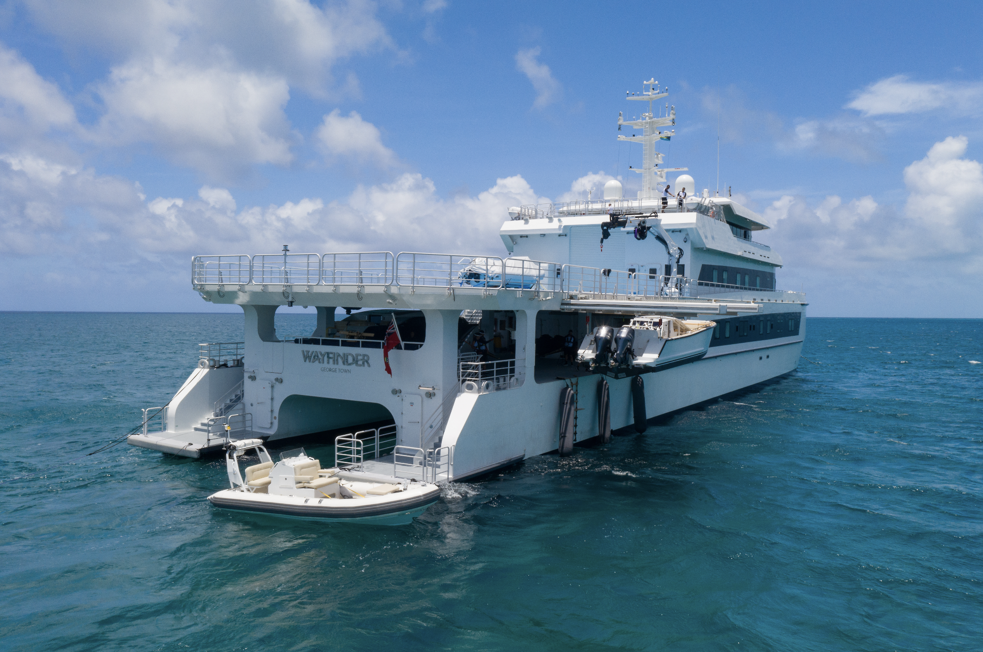 Large white yacht named Wavfinder on open water under a partly cloudy sky.