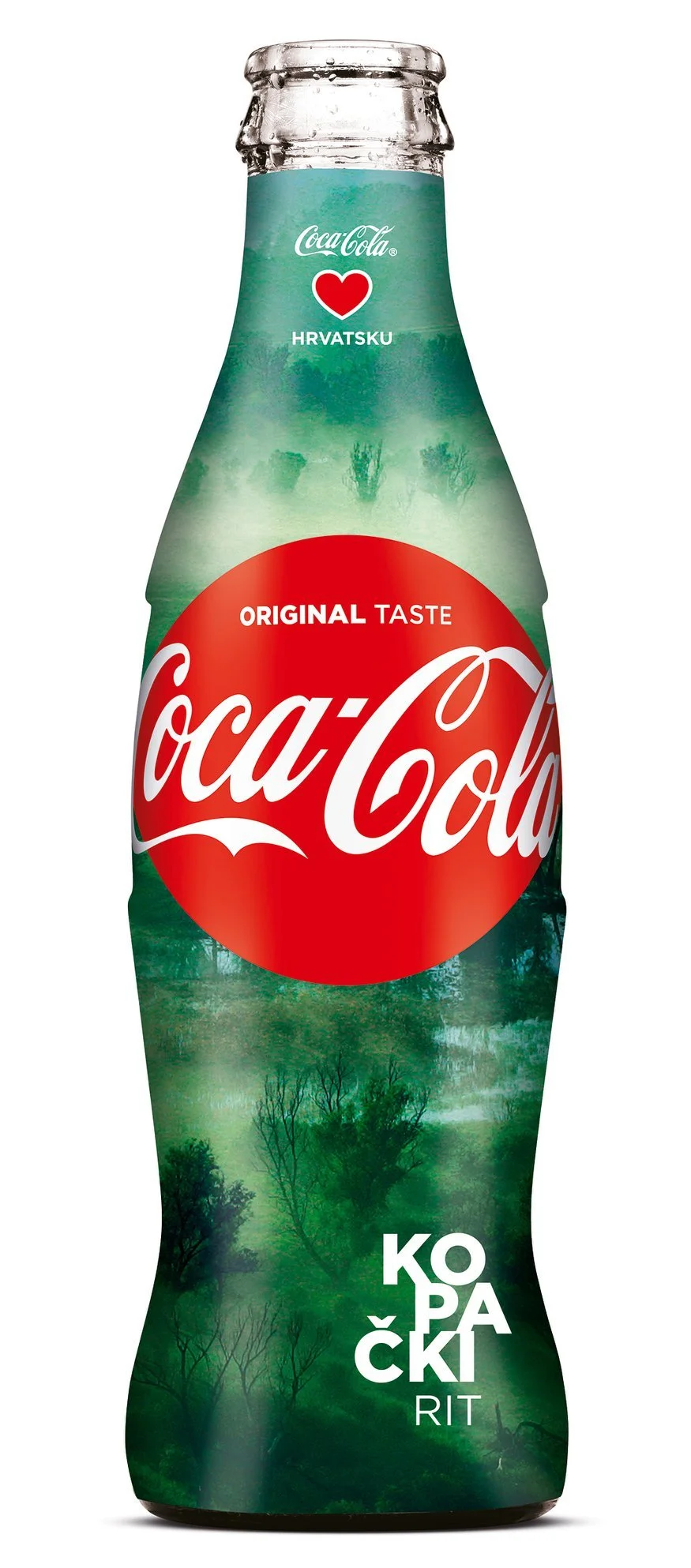 A Coca-Cola bottle with a landscape of a forest and fog inside the bottle, featuring trees and mist, and text in Croatian.