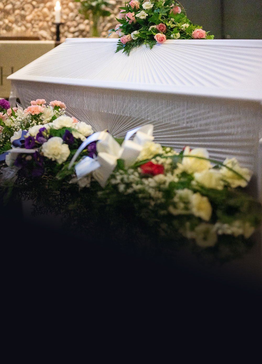 Kuva kukkien ympäröimästä valkoisesta arkusta.