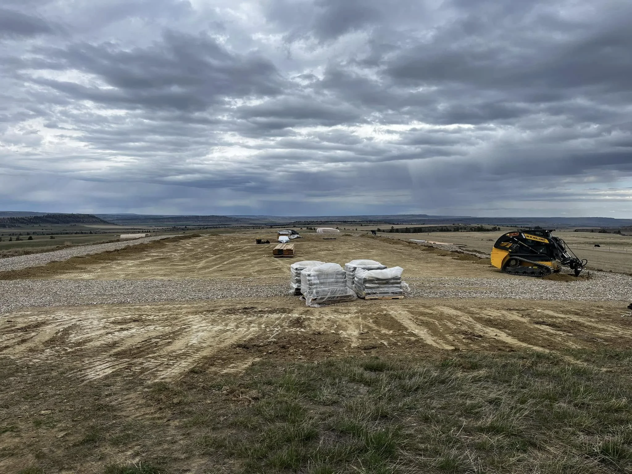 Construction site with a small tracked bulldozer and stacks of wrapped materials 