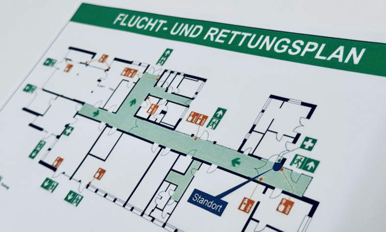 Flucht- und Rettungsplan zeigt den Fluchtweg durch das Gebäude sowie Notausgänge, Erste-Hilfe-Stationen und Feuerlöscher.