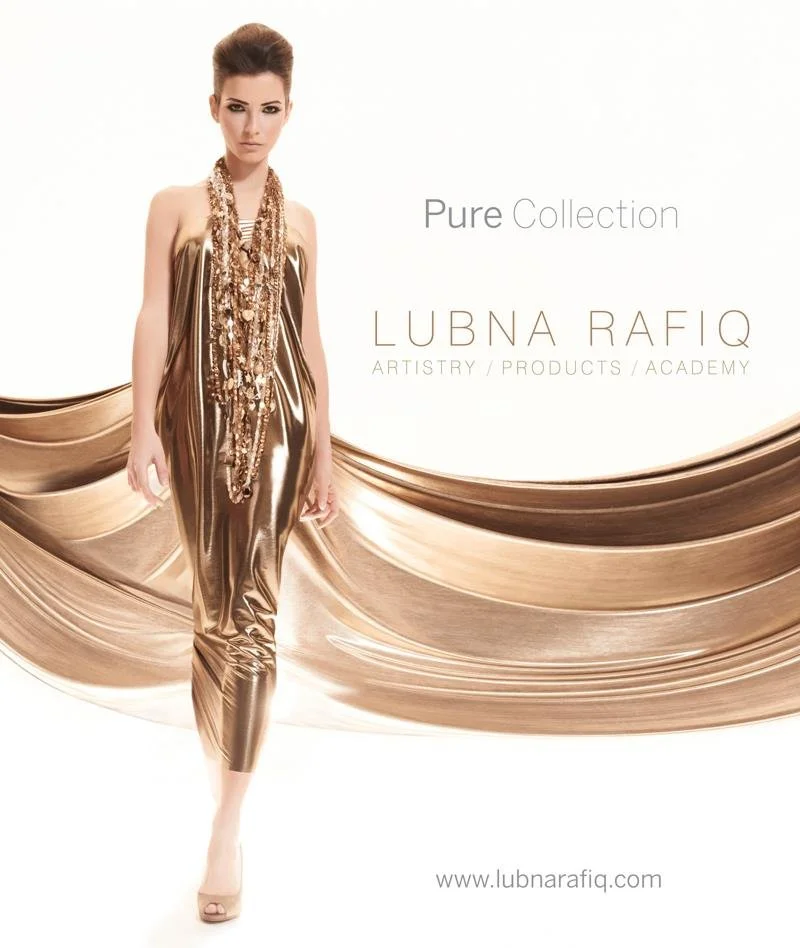 A woman wearing a shiny gold dress poses in front of a white background with gold fabric flowing behind her. The text says 'Pure Collection' and 'Lubna Rafiq ARTISTRY/PRODUCTS/ACADEMY'.