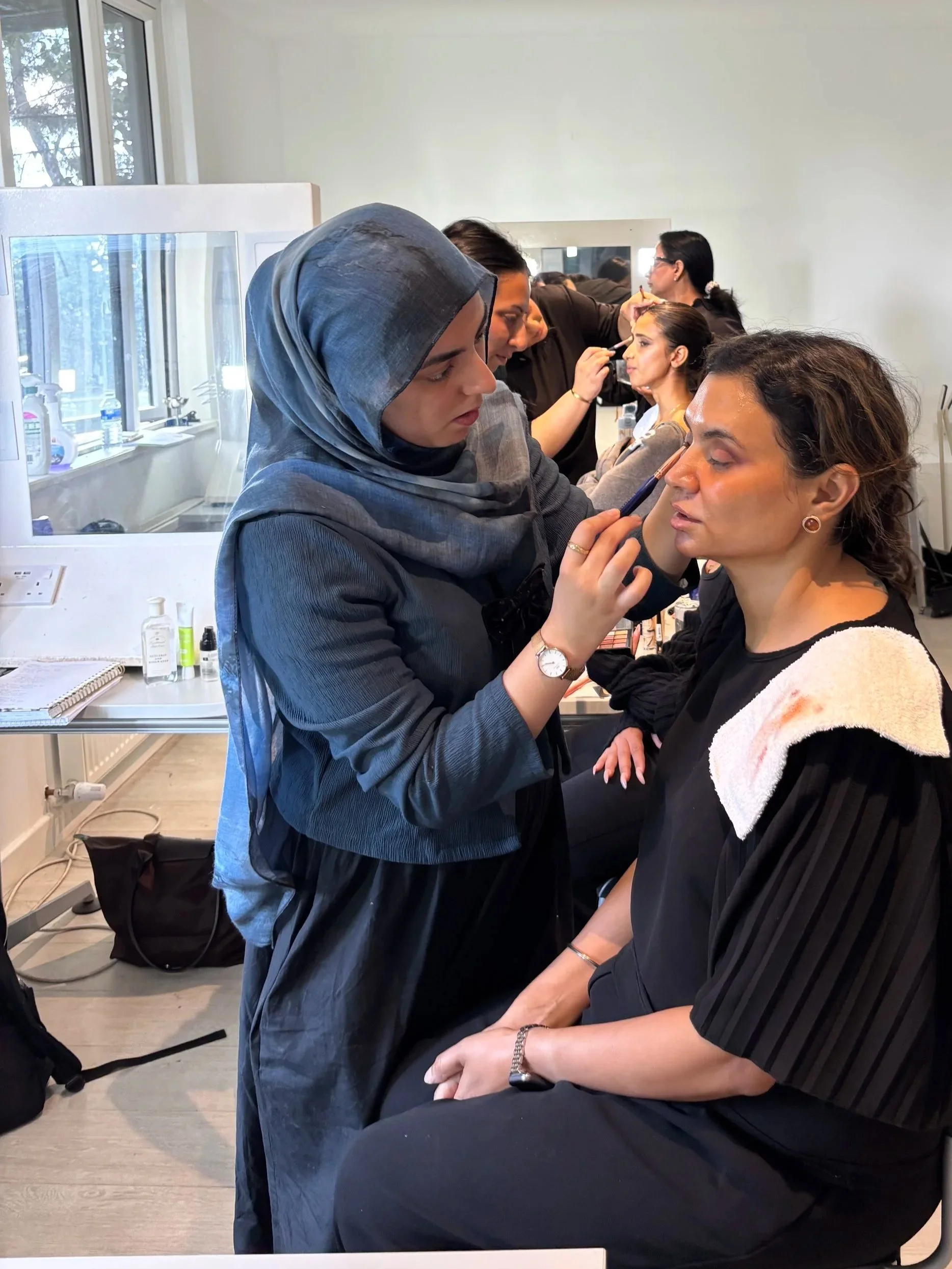 A woman receiving makeup application from a makeup artist in a makeup studio.