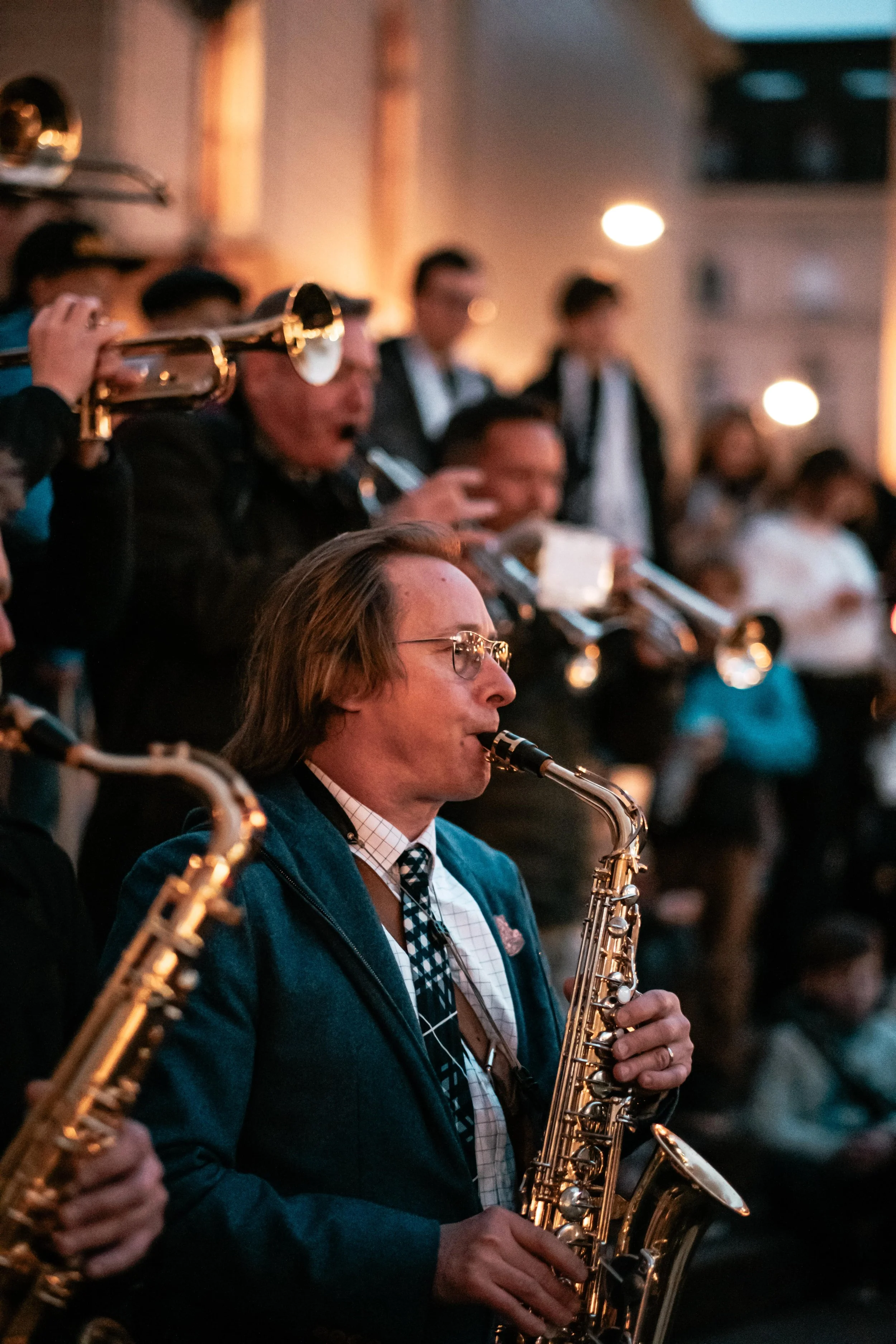 Musiker spielt Saxophon während eines Live-Konzerts im Freien bei Nacht, im Hintergrund Publikum und weitere Musiker.