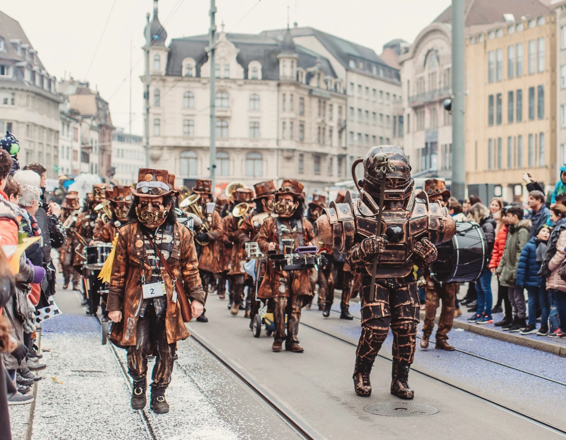Menschen in Steampunk-Kostümen bei einer Parade in einer Stadt mit historischen Gebäuden.