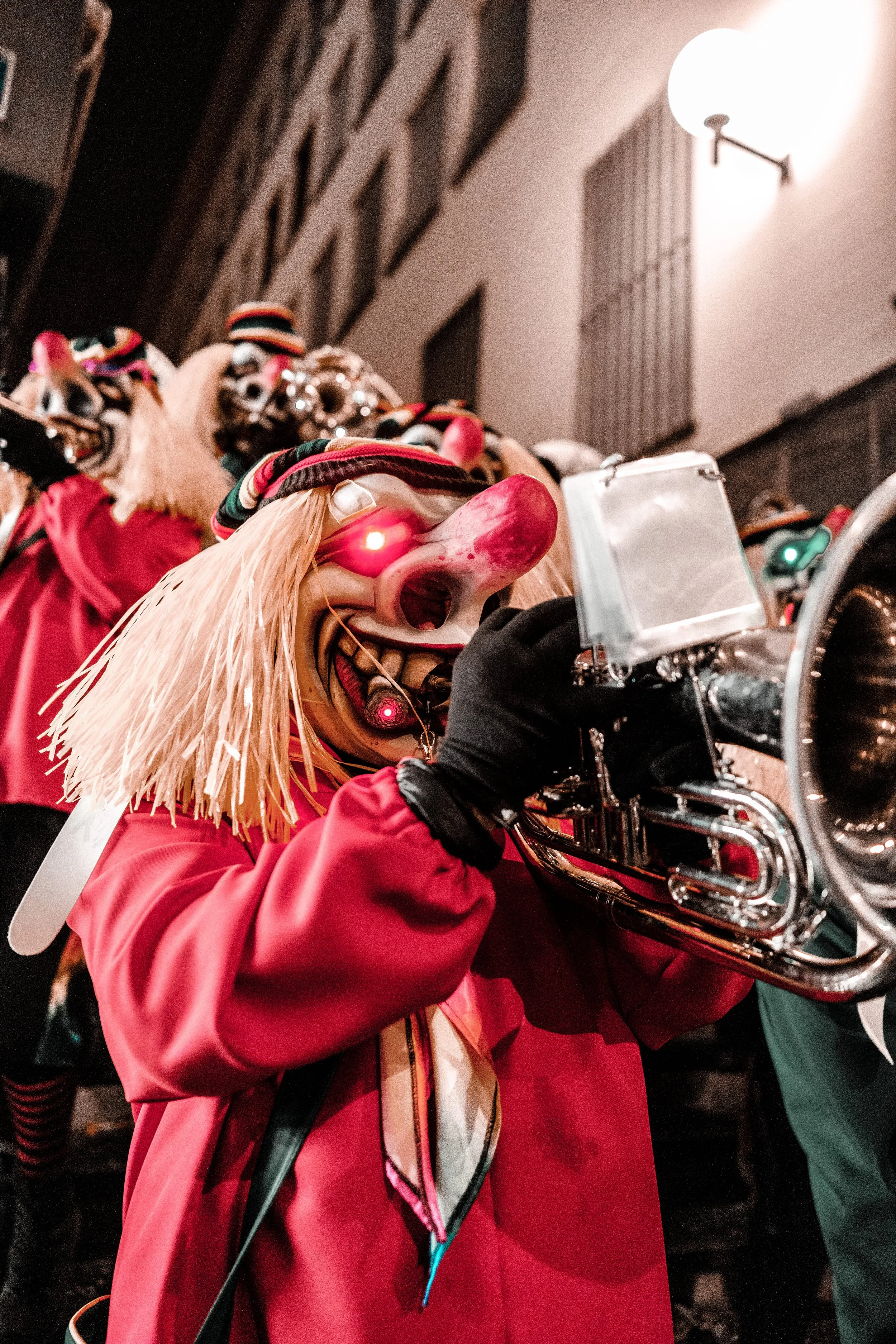 Person in Clownkostüm spielt Trompete bei einer nächtlichen Feier