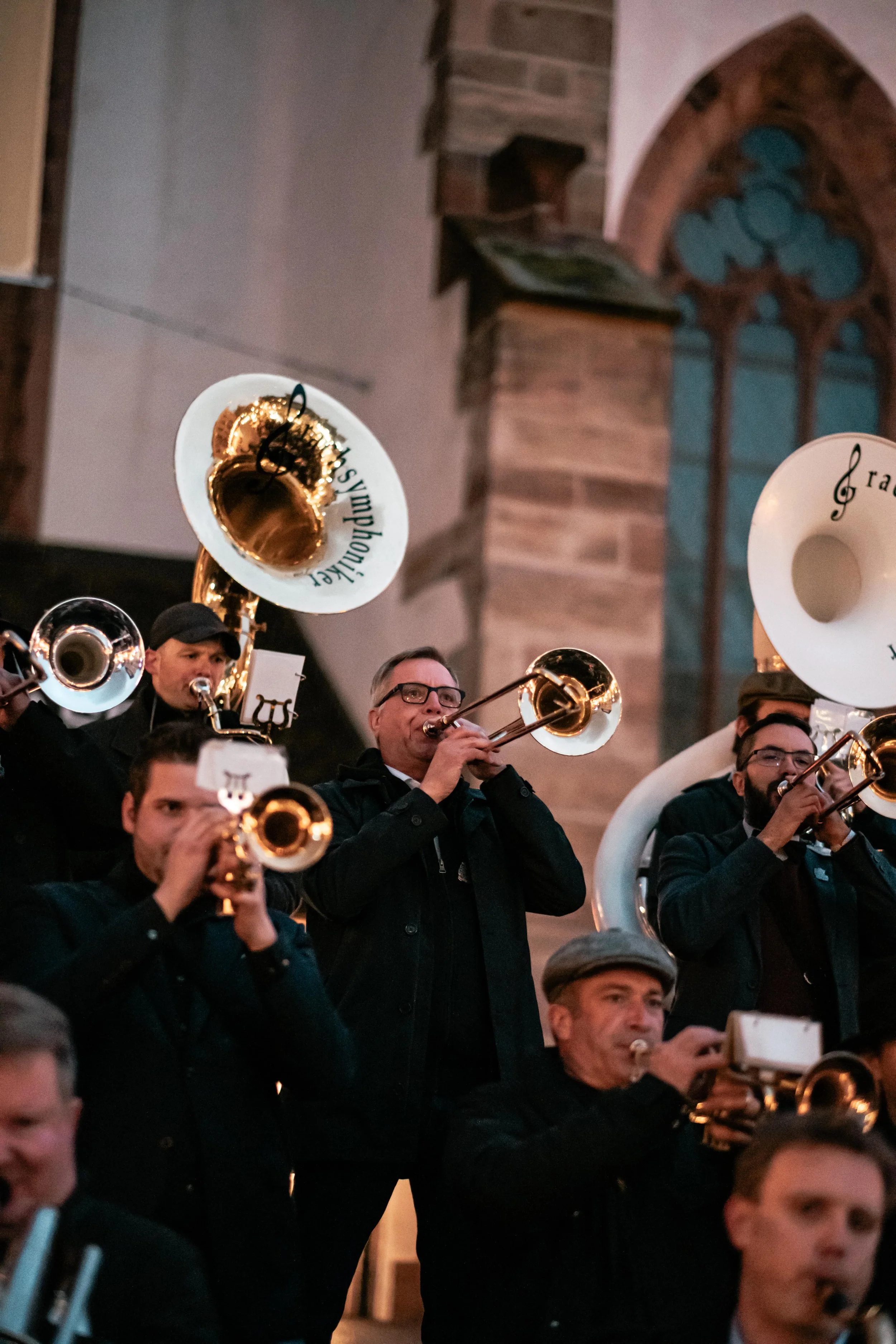Musiker in einer Kirche spielen Blechblasinstrumente bei einem Orchesterkonzert.