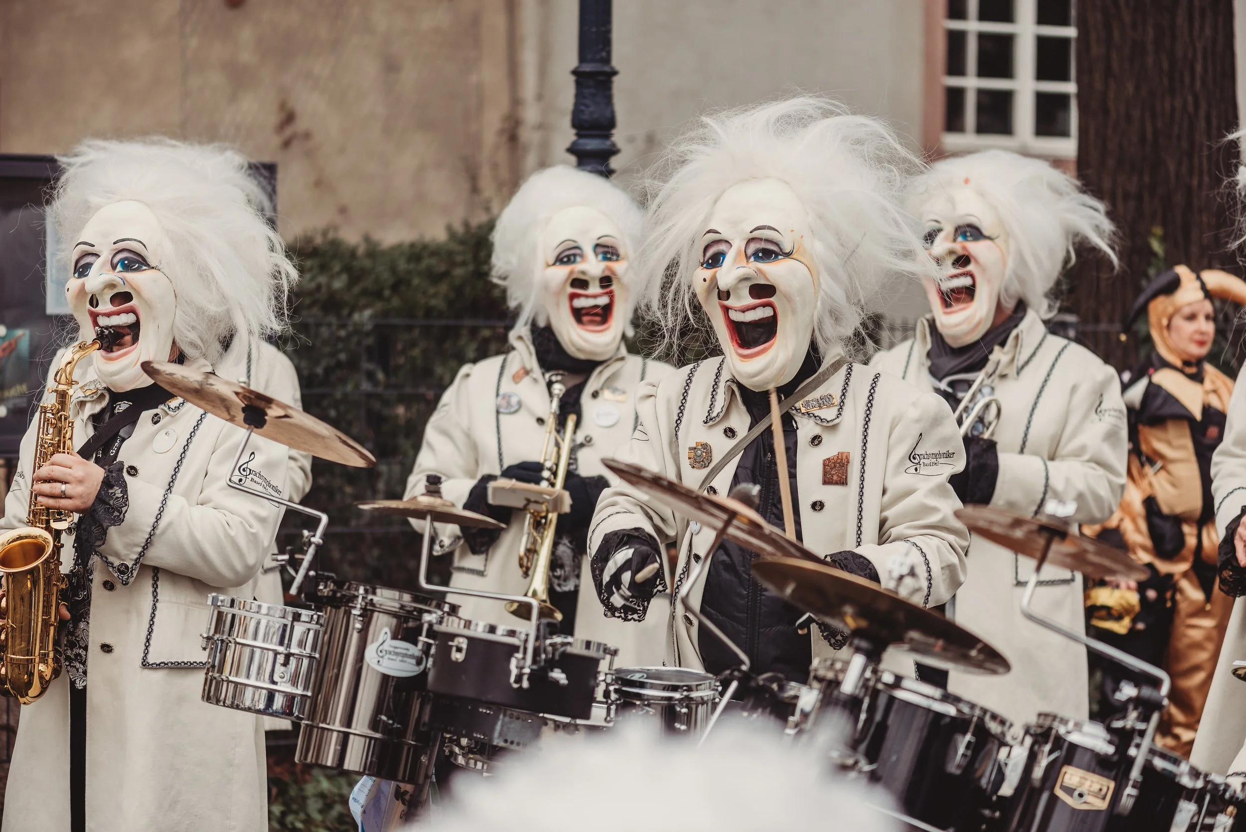 Menschen in Kostümen mit weißen, gruseligen Masken spielen in einer Band und spielen Musikinstrumente.