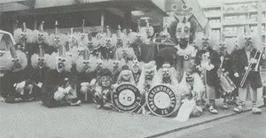 Eine Gruppe von Kindern und Erwachsenen, die mit Spielzeugen und kleinen Zügen vor einem Gebäude posieren.