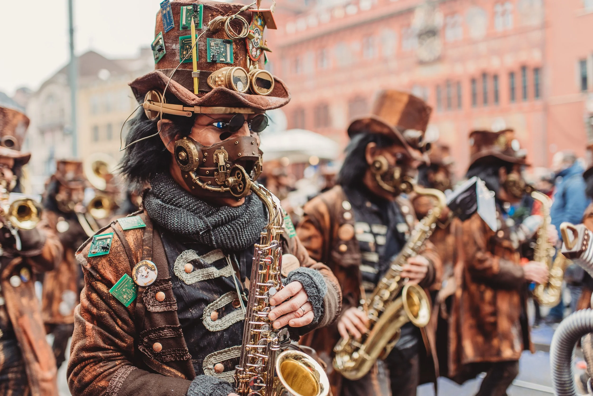 Menschen in Steampunk-Kostümen, die auf einer Parade Musik spielen, tragen viktorianische Kleidung mit zahlreichen Zubehörteilen, Masken, Hüten und elektronischen Elementen.