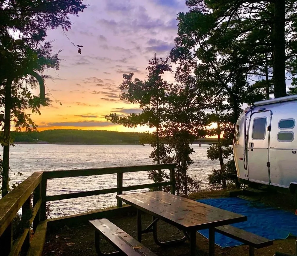 Riveted trailer beside trees at sunset