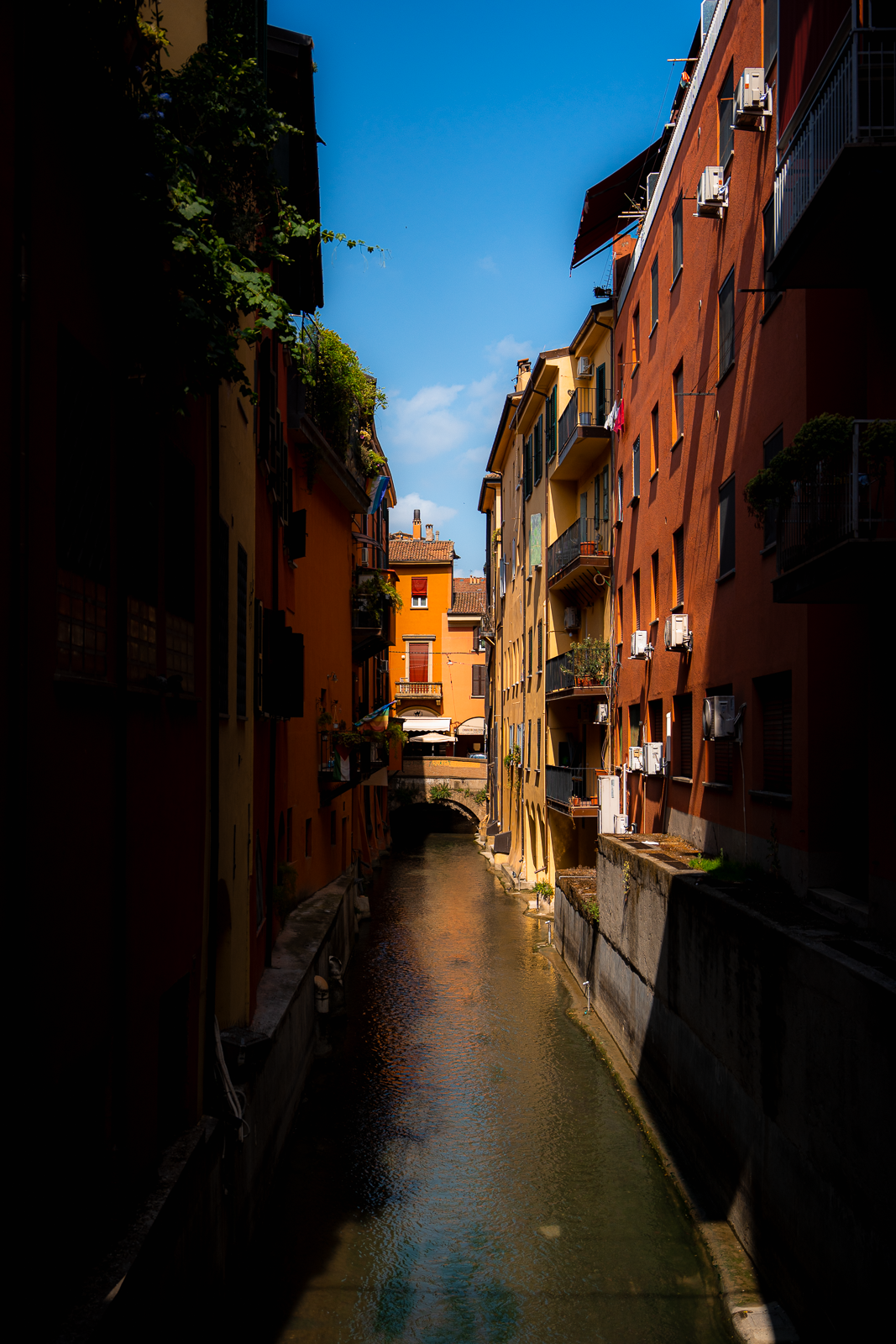 Colorful buildings lining a narrow canal in a European city, with blue sky overhead.