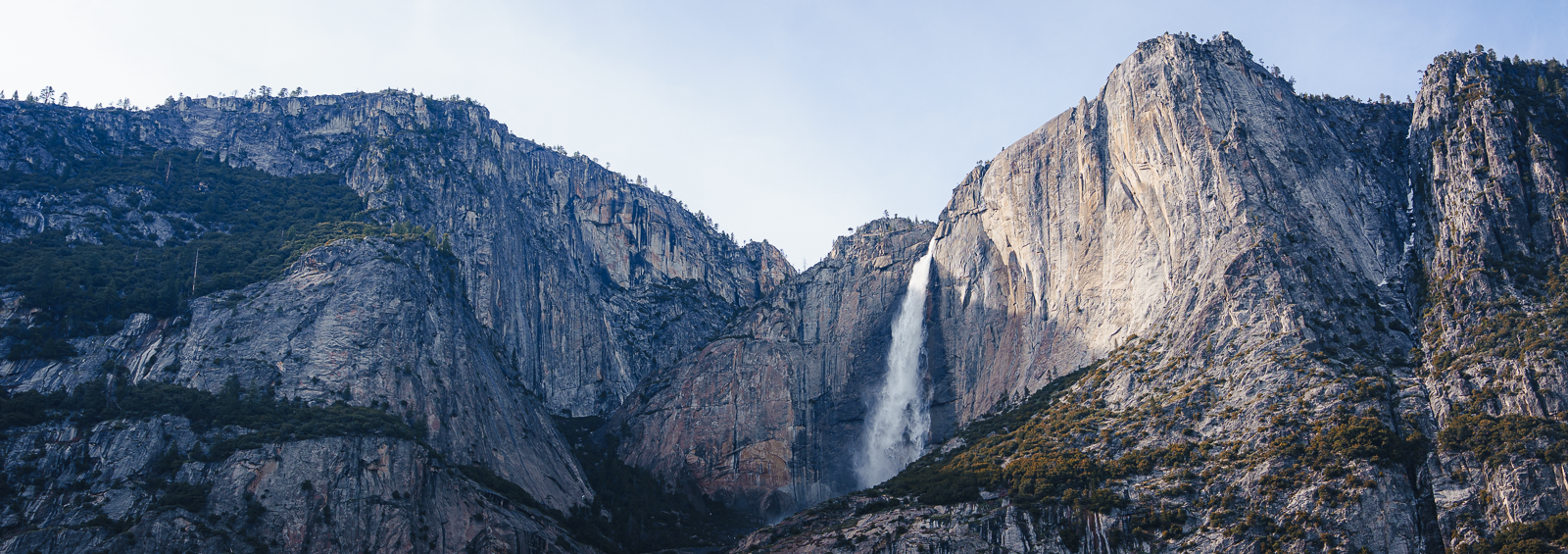 A mountain landscape with steep rocky cliffs and a waterfall cascading down the center.