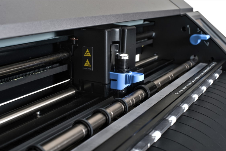 Close up of the blade carriage and rollers on a precision vinyl cutting machine used for custom apparel.
Elite Design precision vinyl cutting plotter at work preparing custom designs.