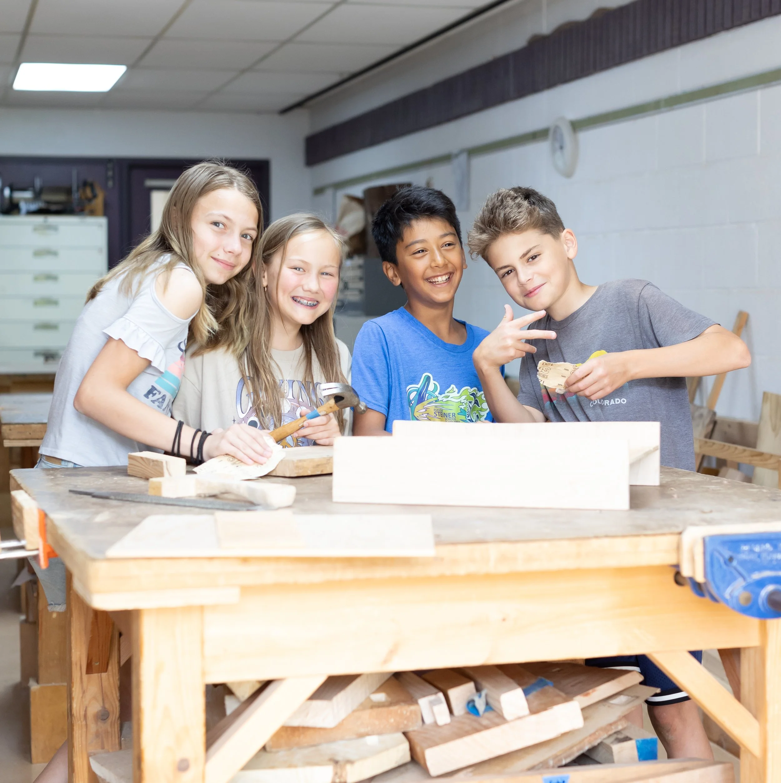 Elementary school students, 2 girls and 2 boys, at the Rudolf Steiner School of Ann Arbor are posing for a photo, smiling in the classroom.