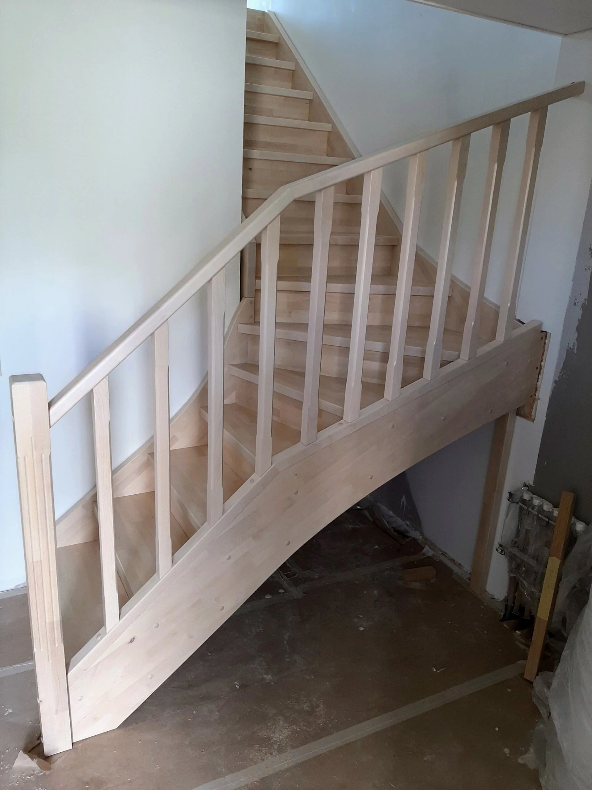Wooden staircase with railing in an unfinished interior space.