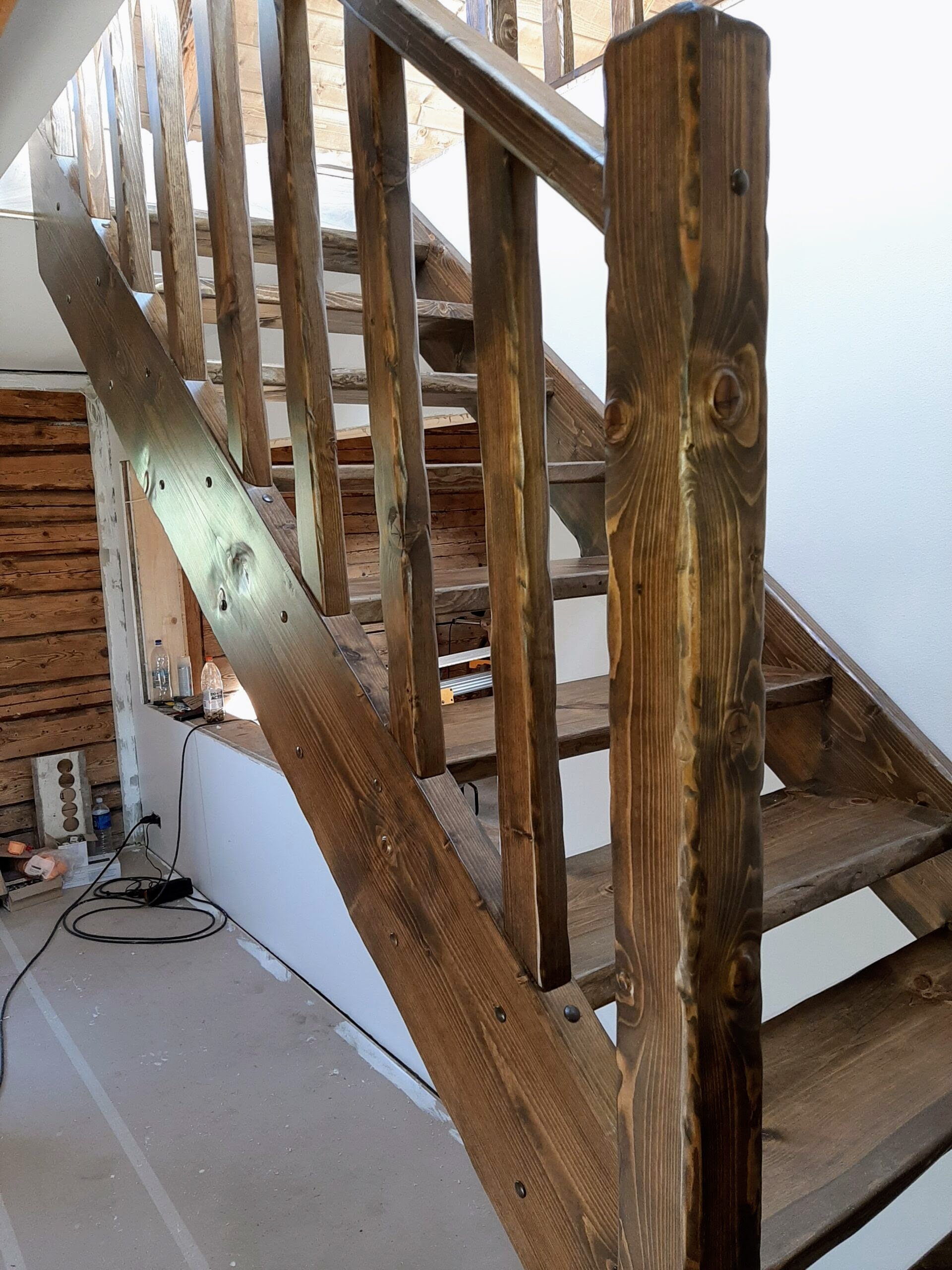 Wooden staircase with unfinished walls and construction materials in the background.
