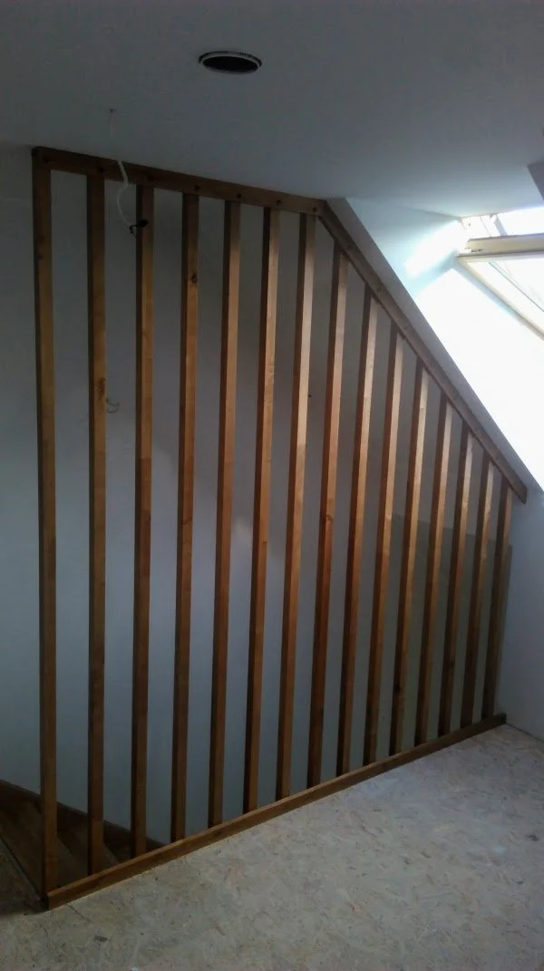 Interior staircase with wooden railing and sloped ceiling with skylight.