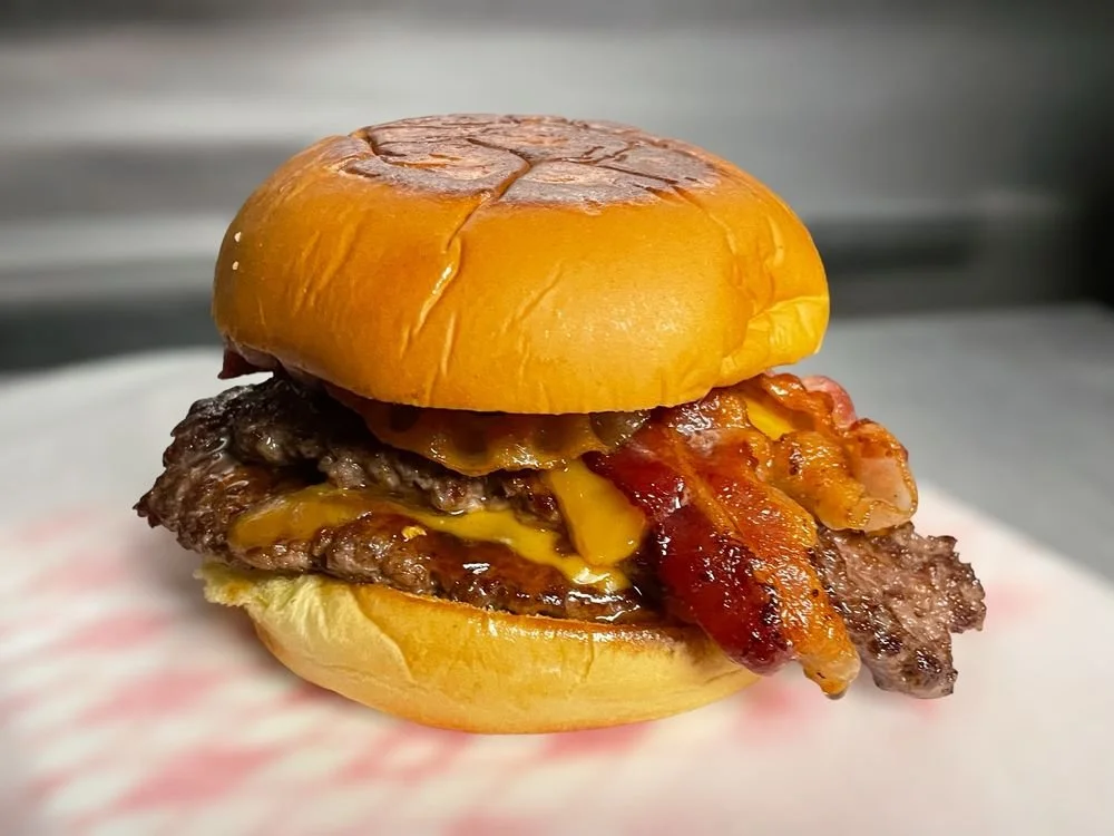 Close-up of a cheeseburger with beef patty, melted cheese, crispy bacon, and a bun.