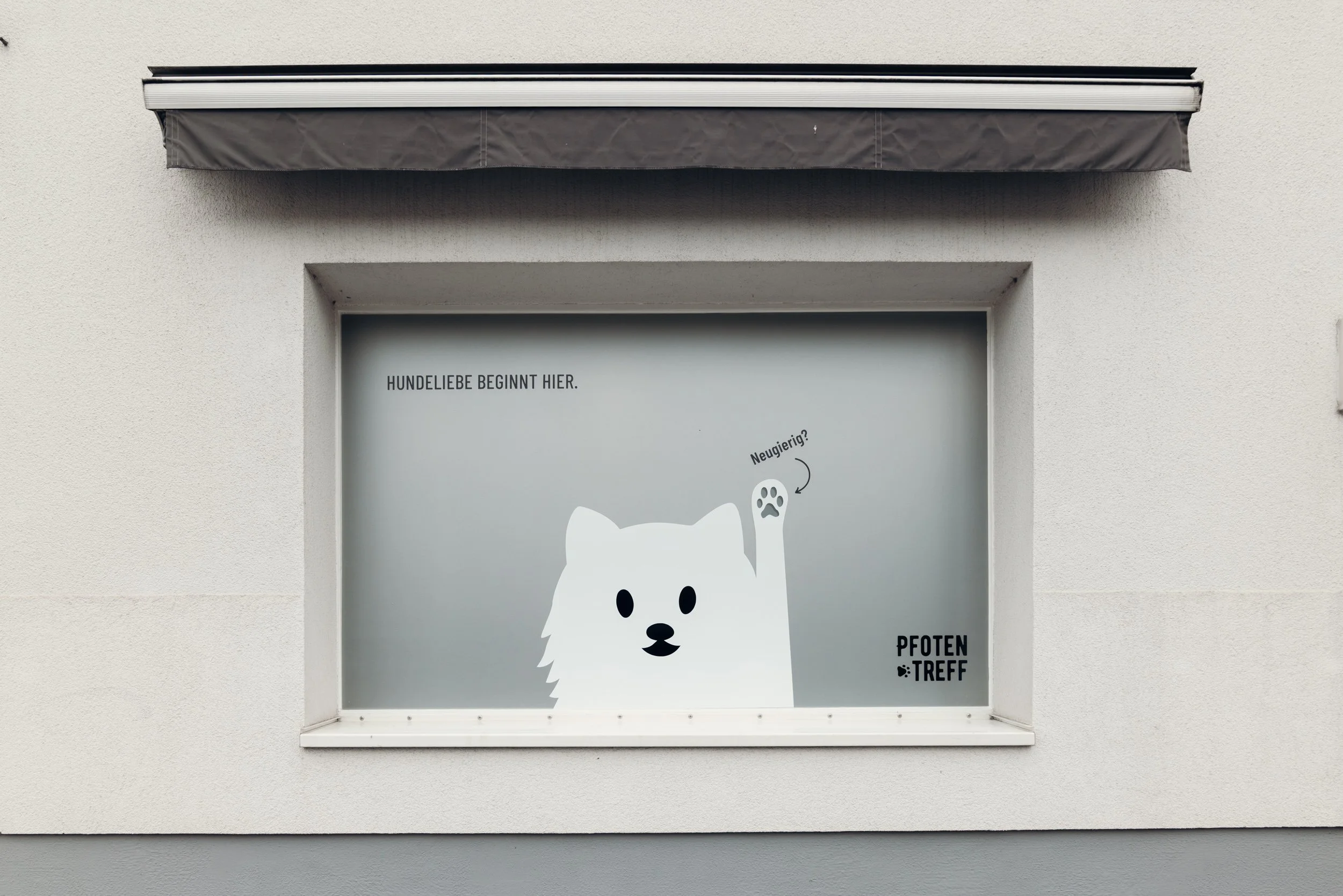 Fenster mit Aufschrift in deutscher Sprache und einer Illustration eines Hundes, der neugierig blickt.
