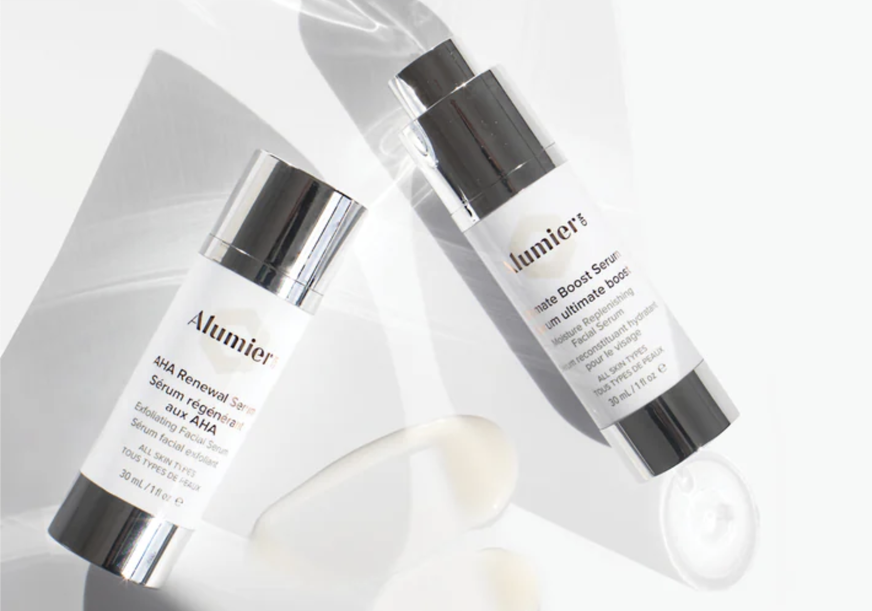 Two bottles of Alumier skincare products.