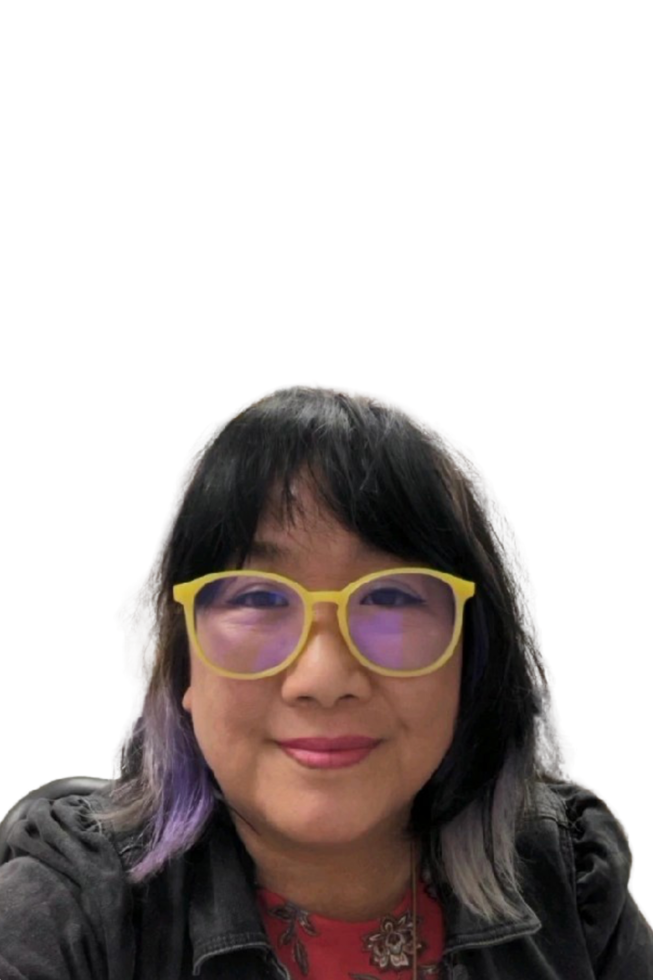 Photo of a woman with black and purple hair wearing large yellow glasses and a denim jacket, smiling against a white background.
